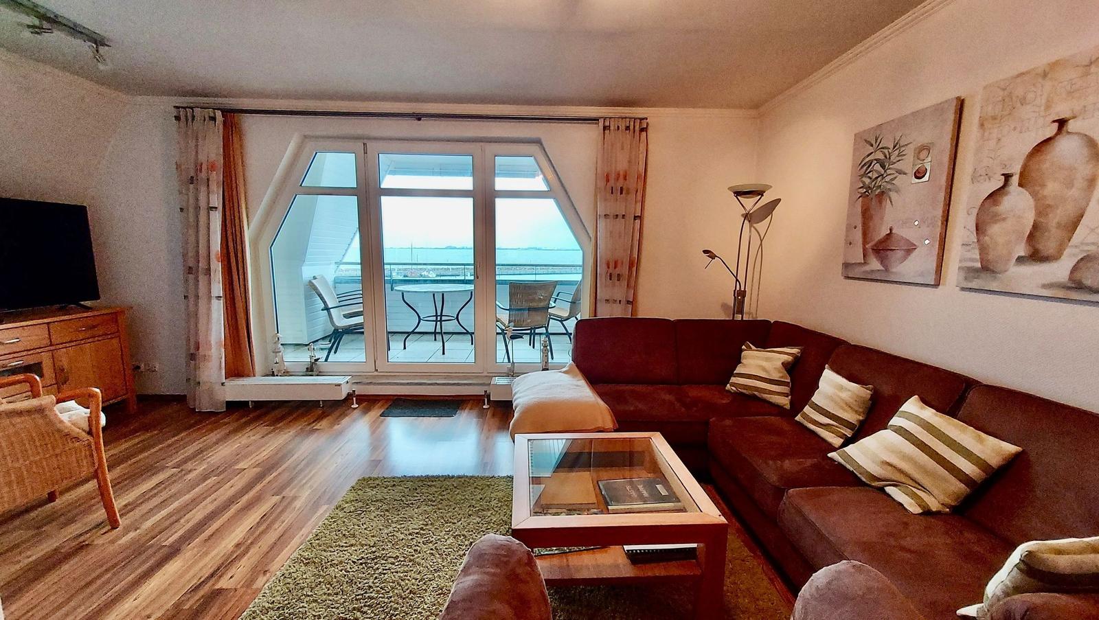 Wohnzimmer mit Sofa, Couchtisch und Balkon mit Meerblick.