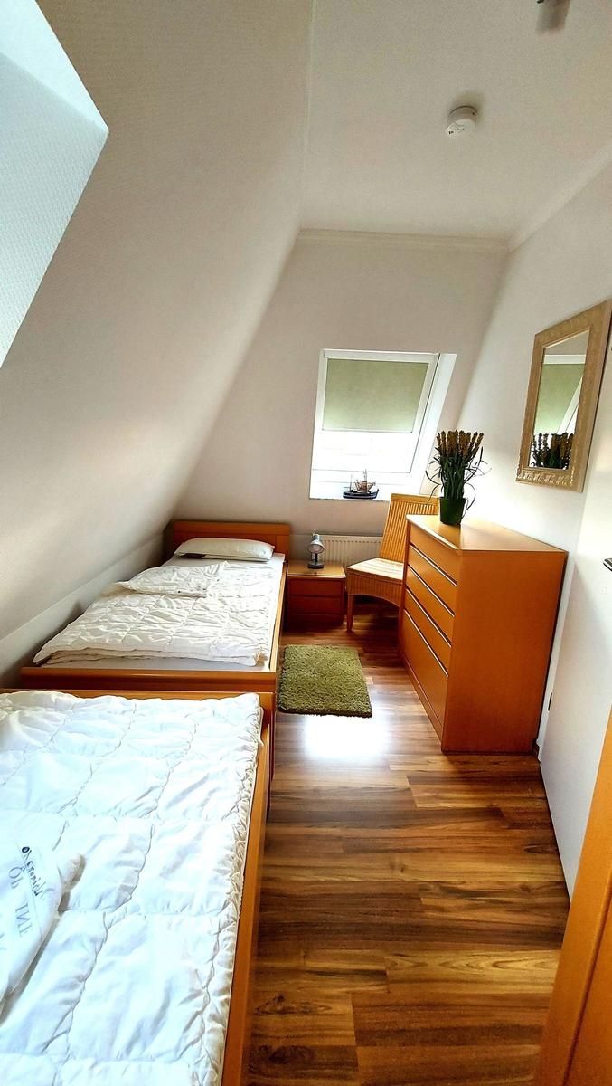 Zimmer mit zwei Betten, Schrank und Fenster unter Dachschrägen.