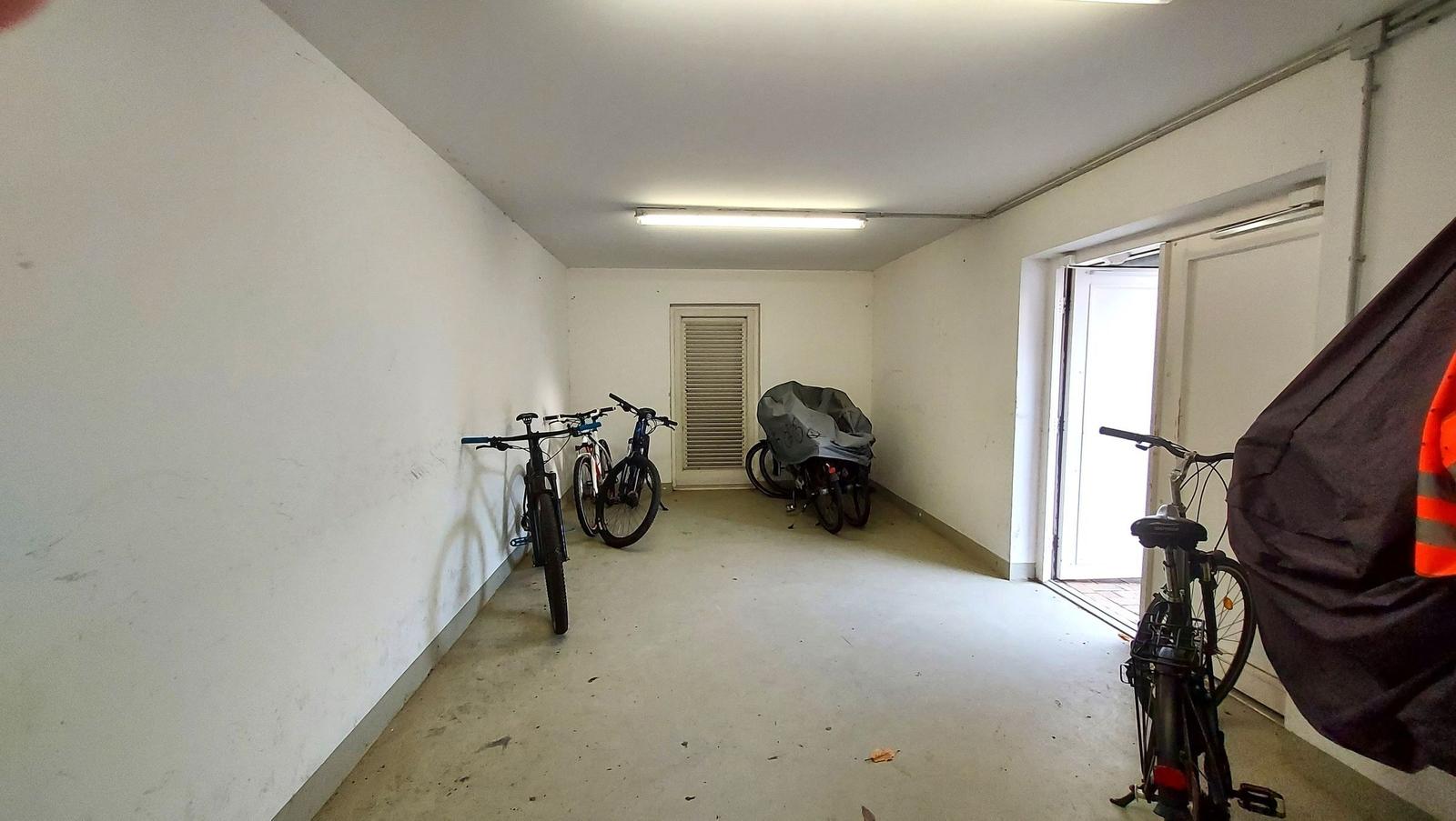Garage mit mehreren Fahrrädern und einer Tür zum Außenbereich.