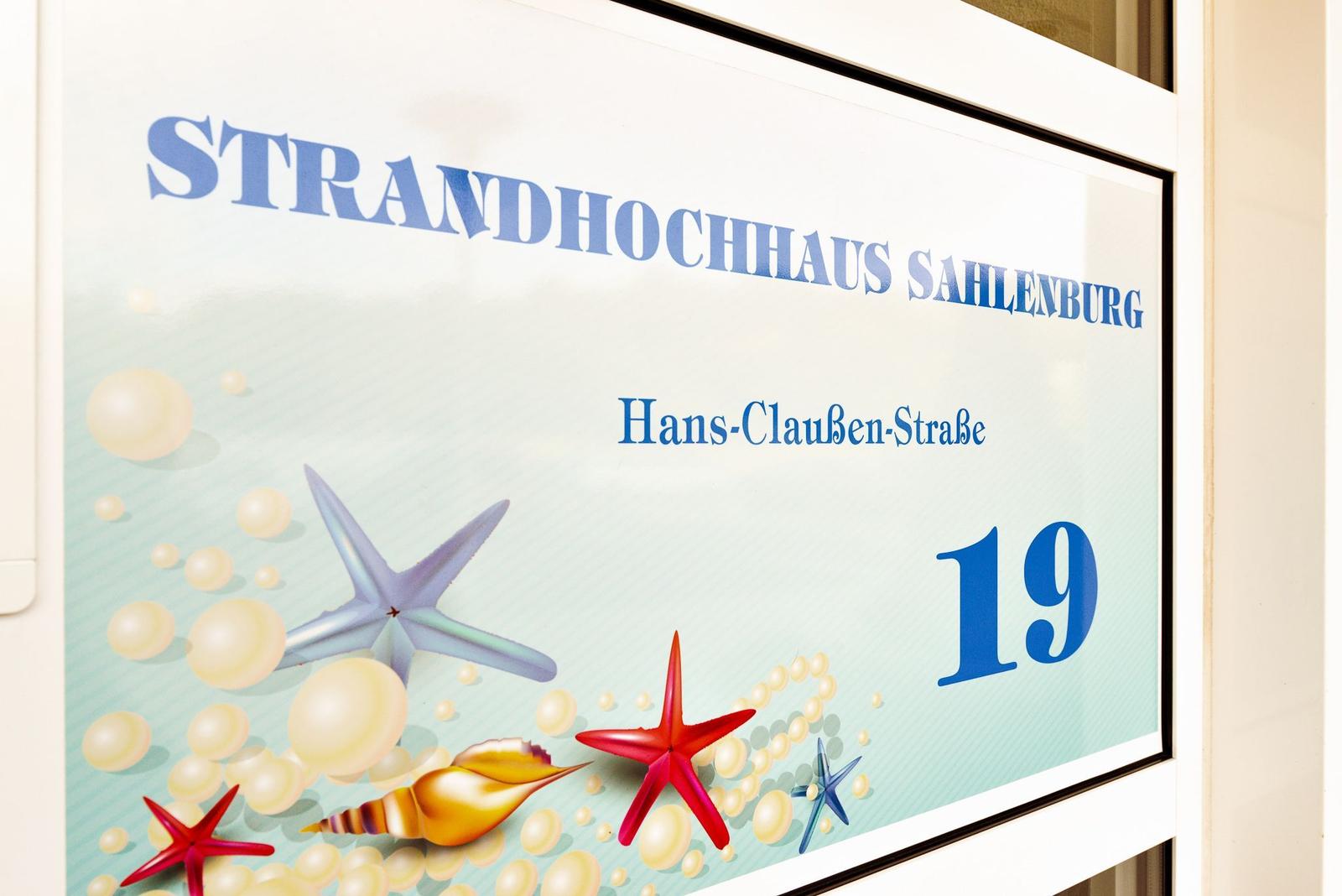 Schild zeigt Strandhochhaus Sahlenburg, Hans-Claussen-Straße 19 mit Meeresmotiven.