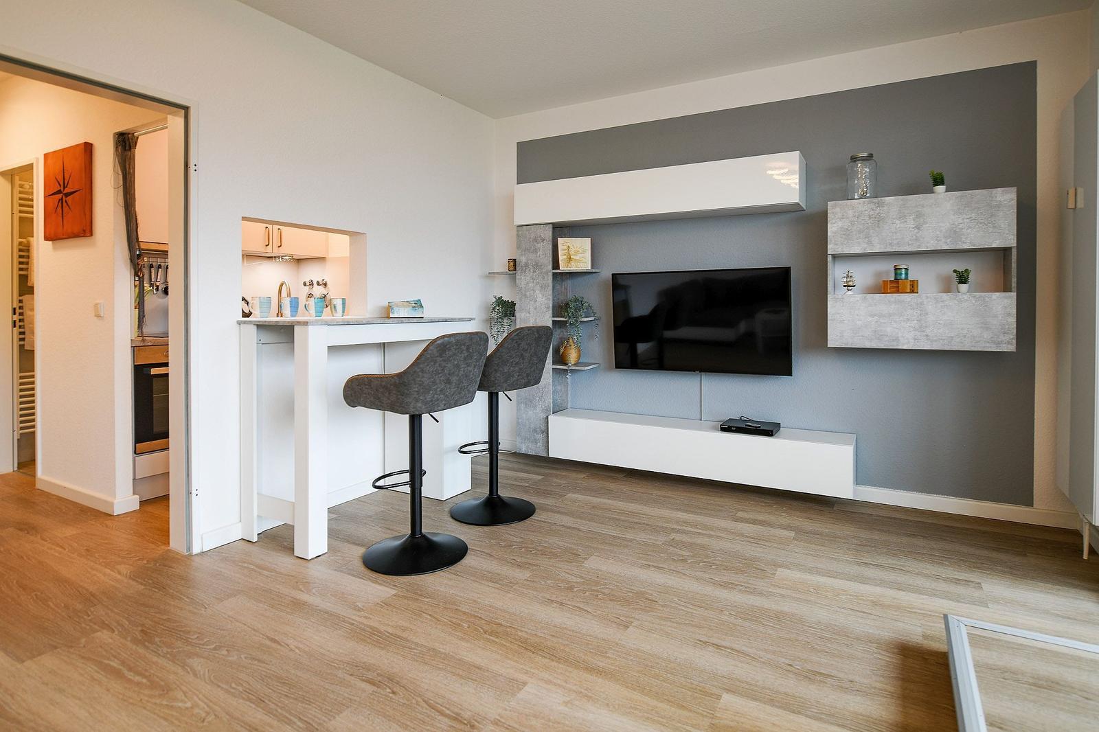 Wohnbereich mit TV, Barhocker und Küchenbereich
