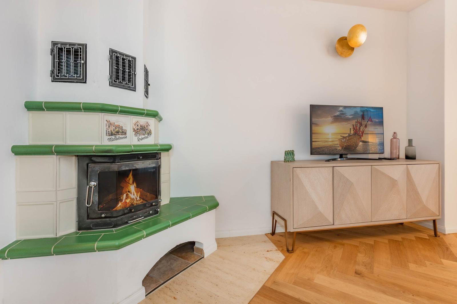 Kamin mit grünen Fliesen und TV auf Sideboard.