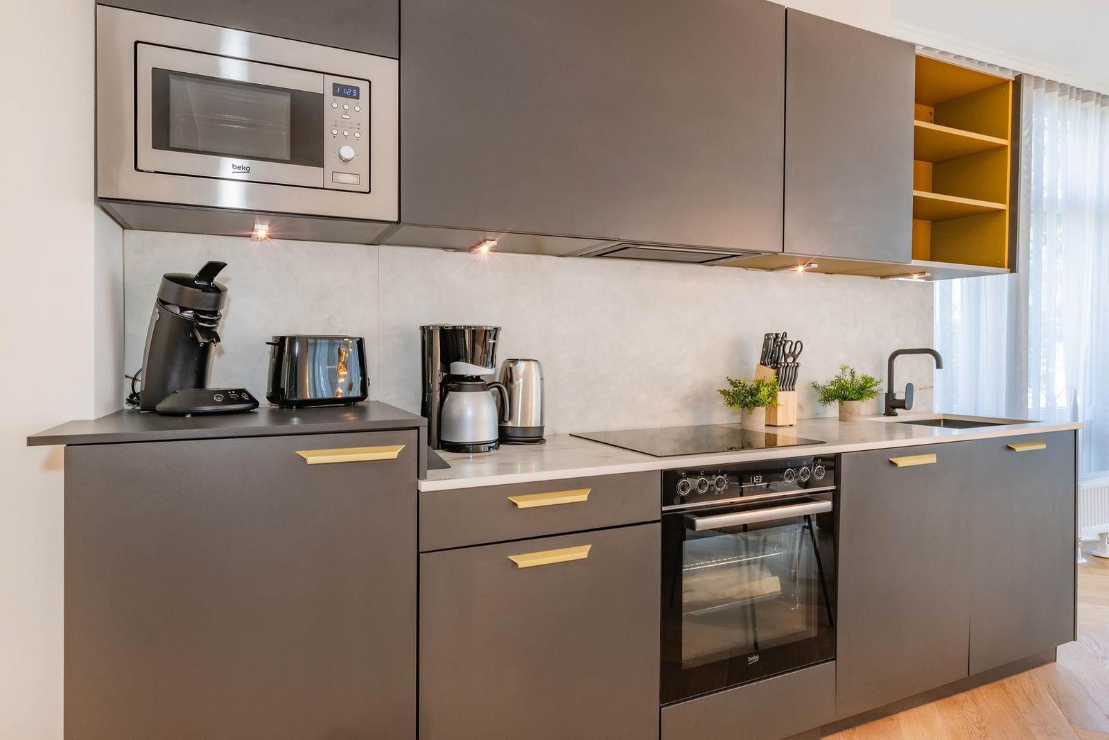 Küche mit Dunstabzug, Herd, Kühlschrank und Arbeitsplatte.