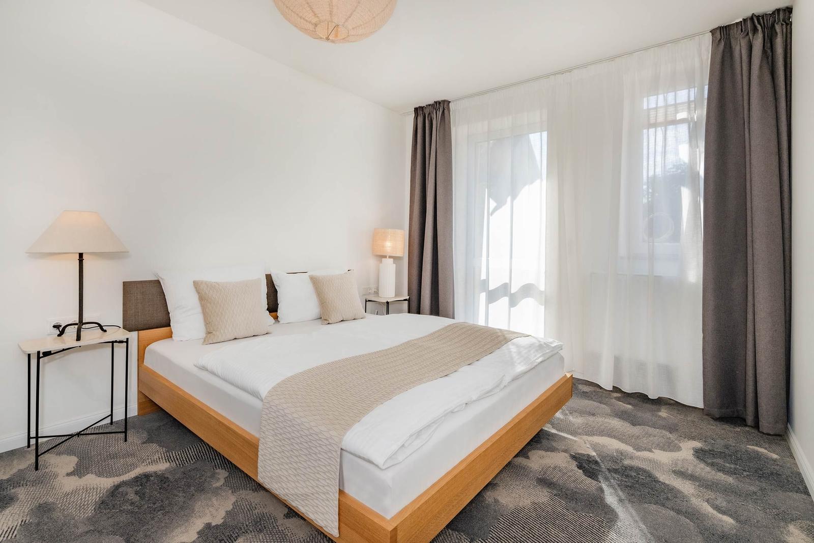 Schlafzimmer mit Bett, Nachttischen und Vorhängen.