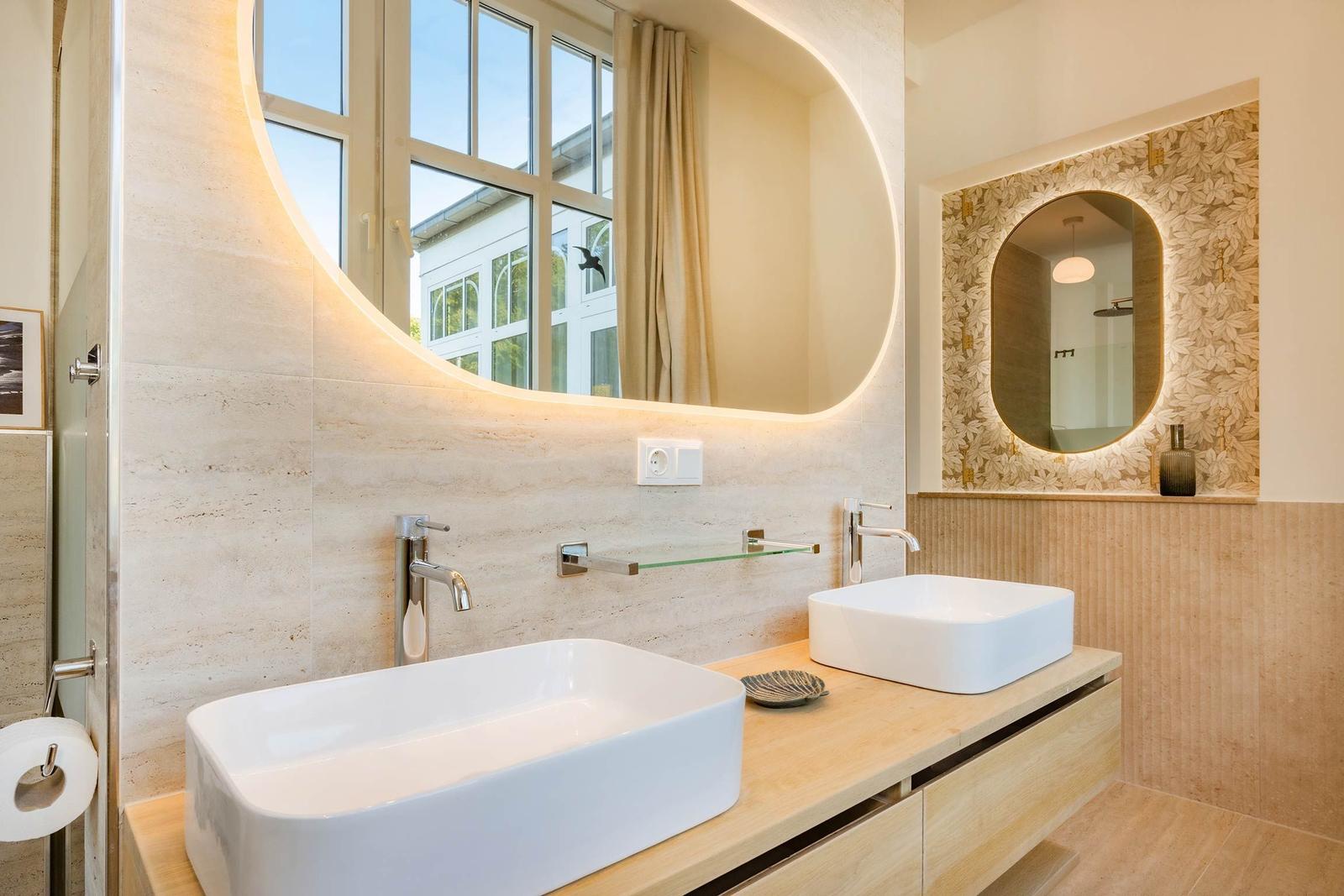 Badezimmer mit zwei Waschbecken, runden Spiegeln und Holzoberfläche.