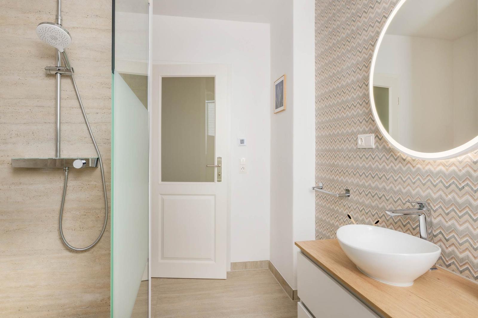 Badezimmer mit Dusche, Waschbecken und Spiegel