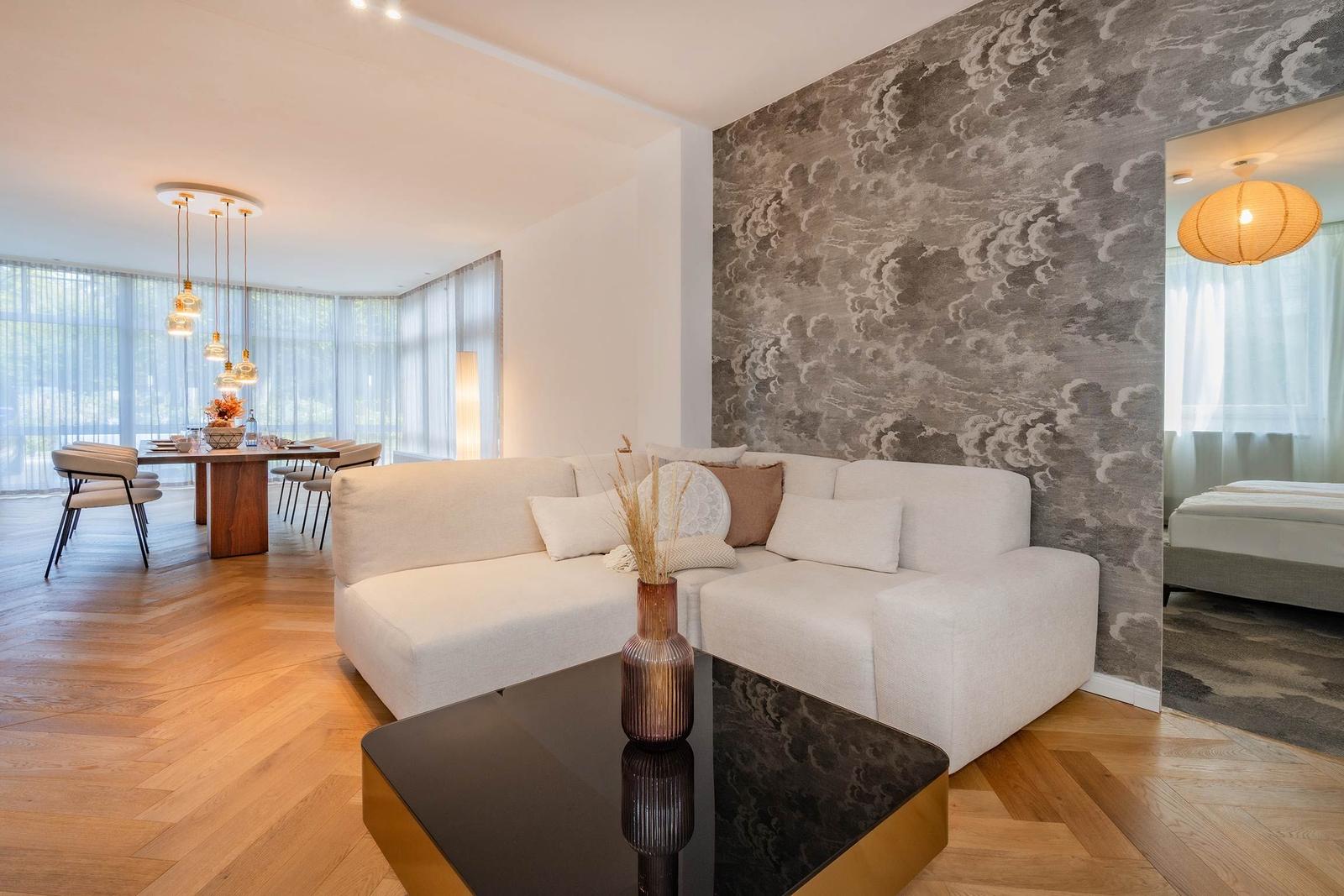 Wohn- und Essbereich mit Sofa, Tisch und Wandtapete.