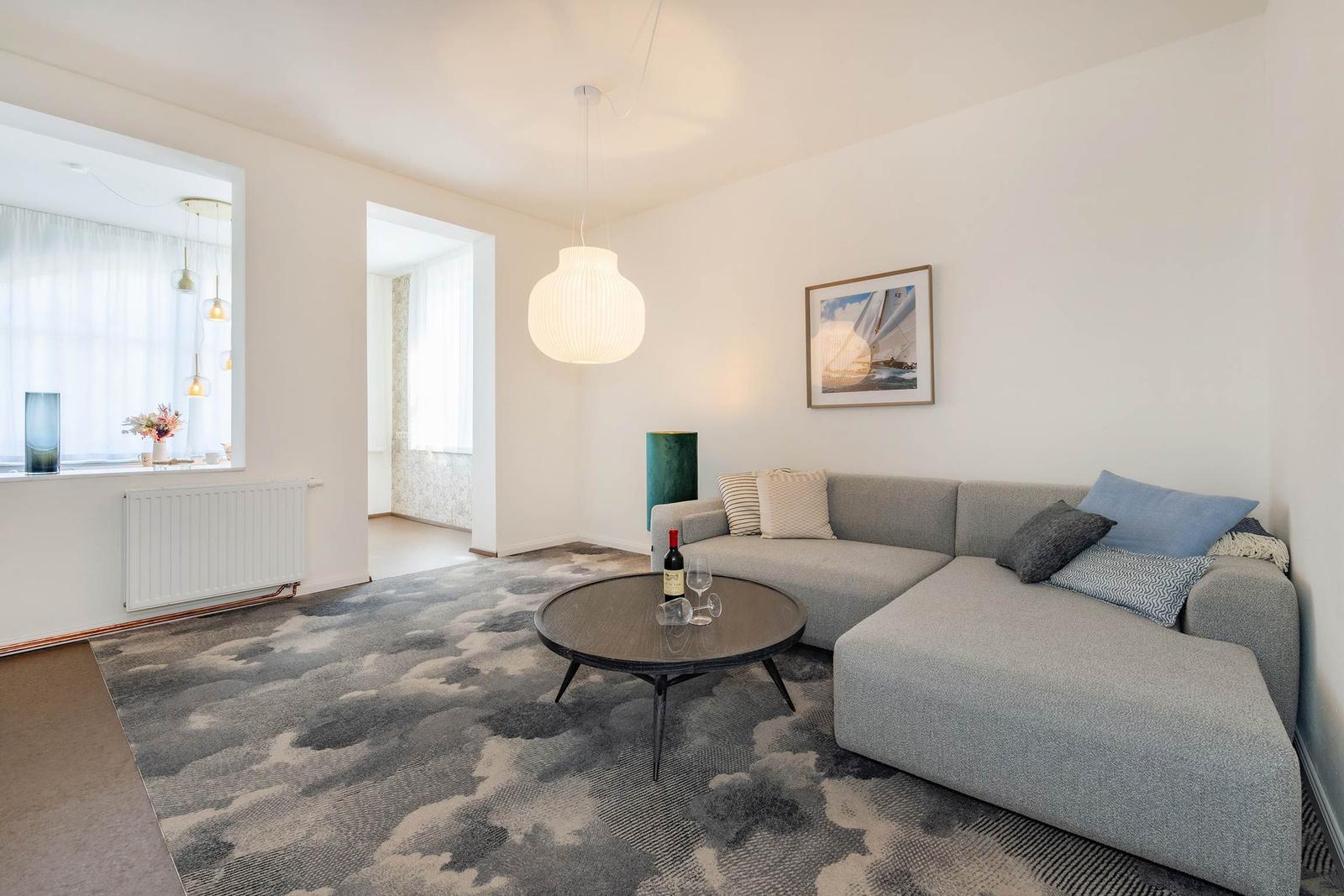 Wohnzimmer mit Sofa, Tisch und Decke. Wandbild und Hängelampe sichtbar.