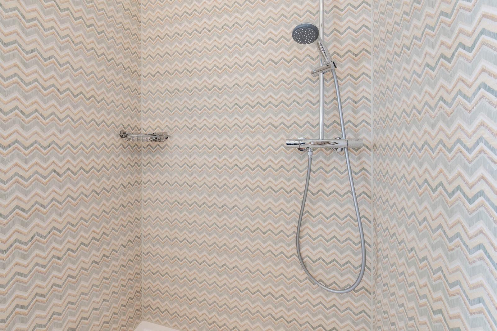 Duschkabine mit wellenförmigem Tapetenmuster und Handdusche