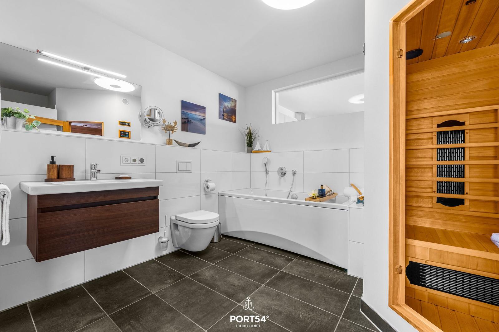 Badezimmer mit Badewanne, Toilette und integrierter Sauna.