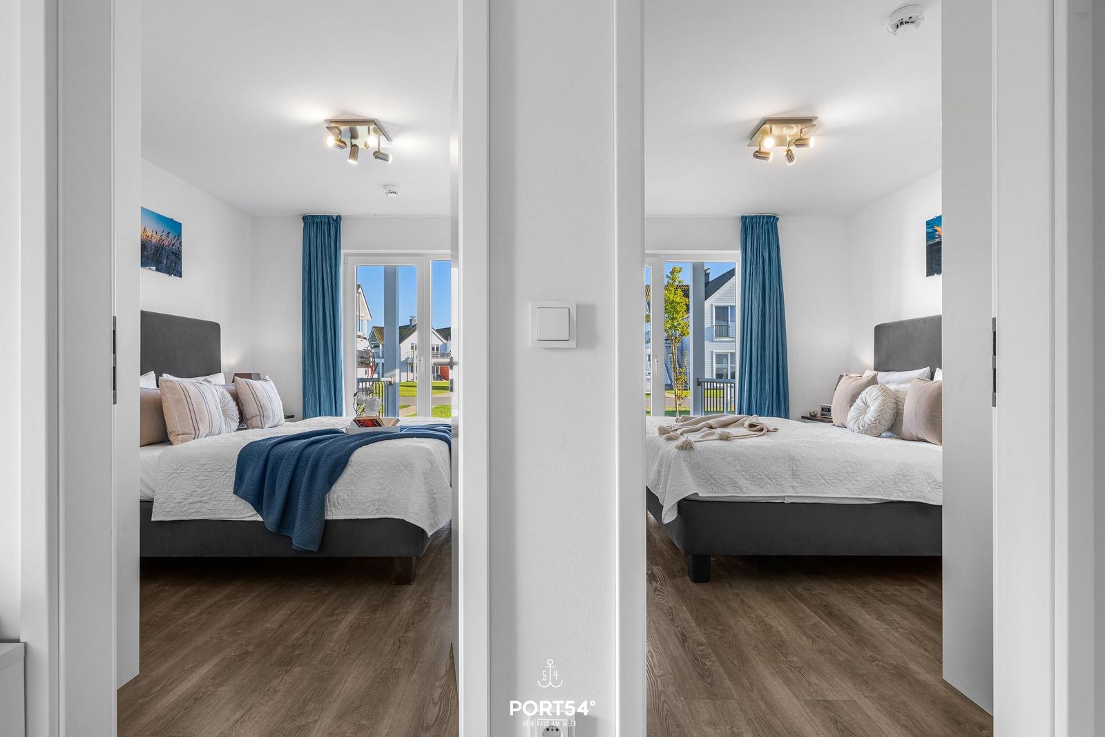 Zwei Schlafzimmer mit Blick auf den Balkon und blaue Vorhänge.