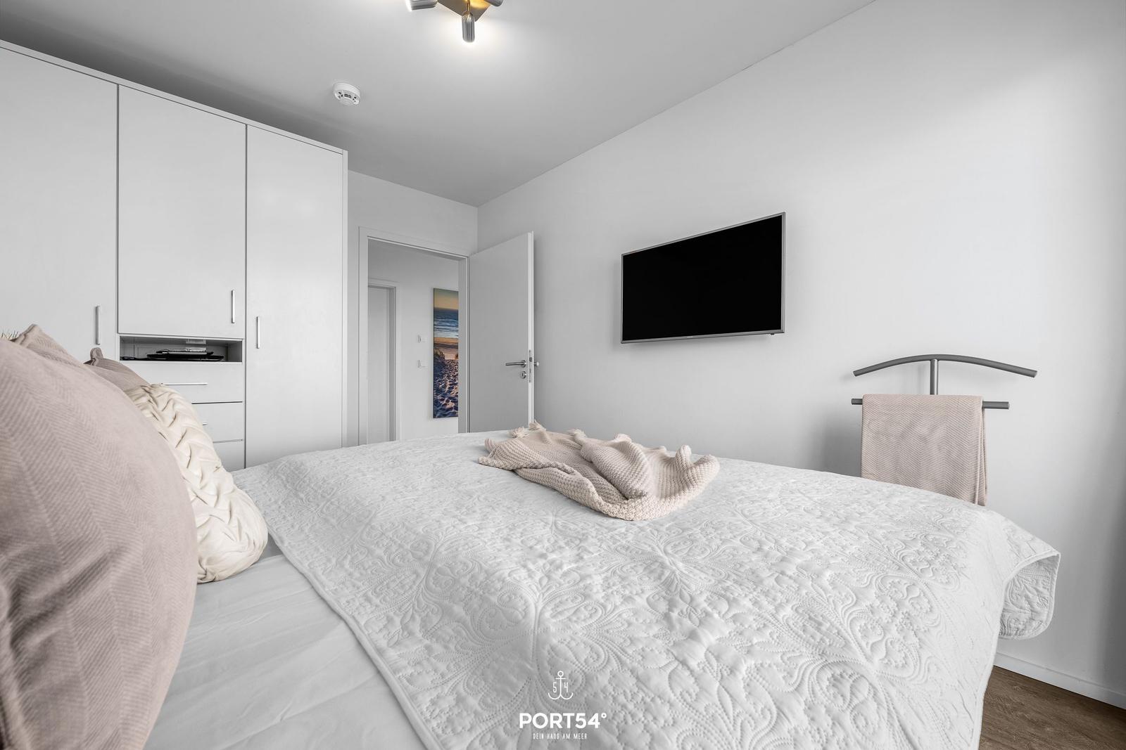 Schlafzimmer mit Bett, TV und Kleiderschrank