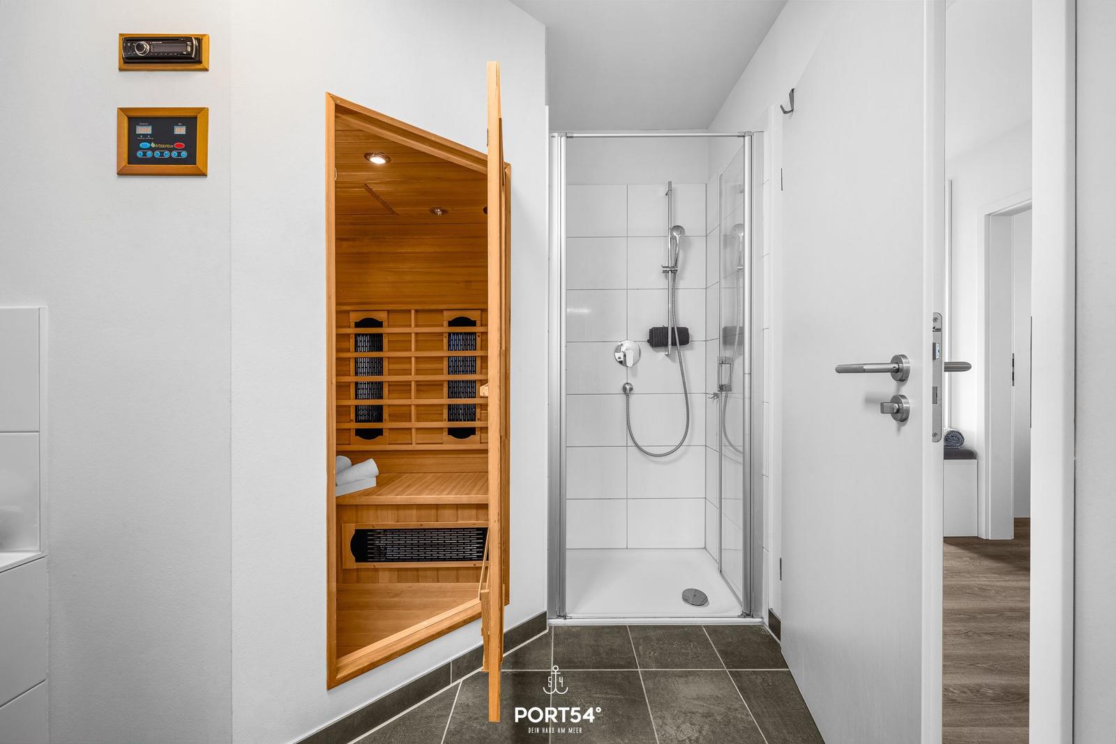 Sauna und Dusche in einem Raum mit Holz und weißen Wänden.