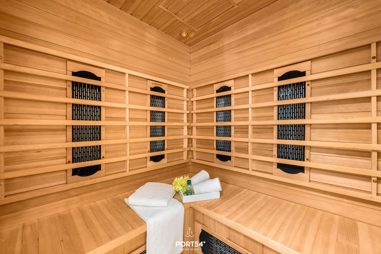 Sauna mit Holzwand und -bänken, weiße Handtücher und eine kleine Deko auf der Bank.