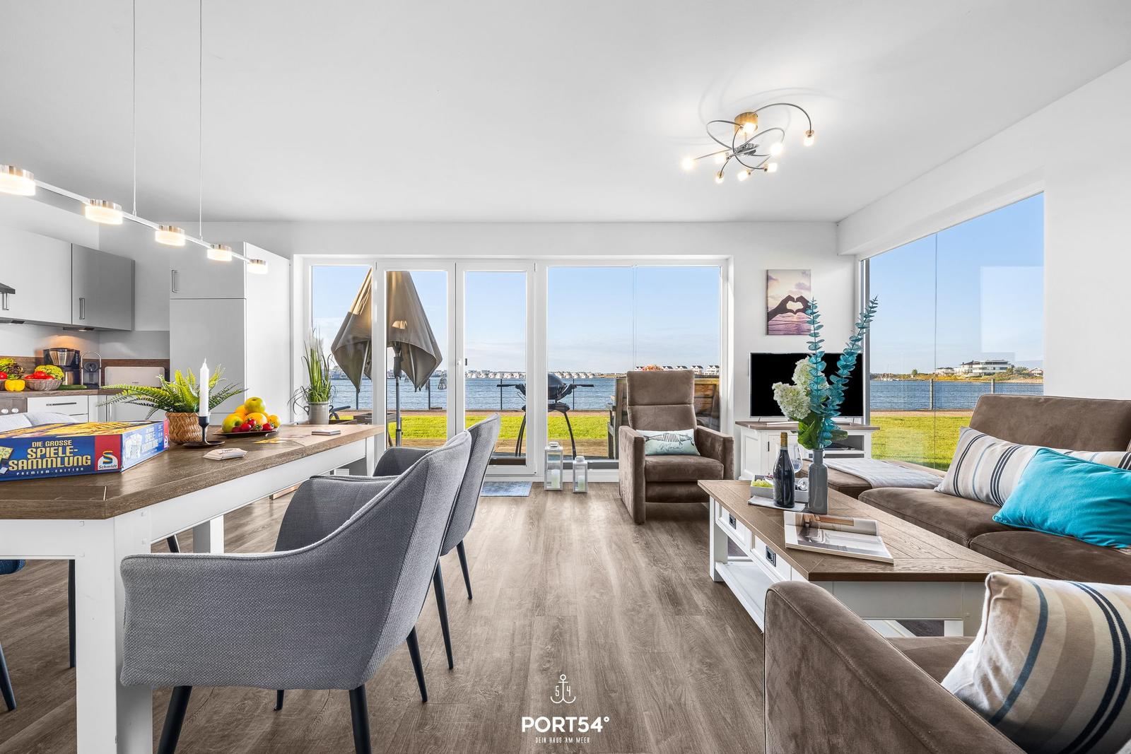 Wohn- und Essbereich mit Meerblick durch große Fenster und Balkon.