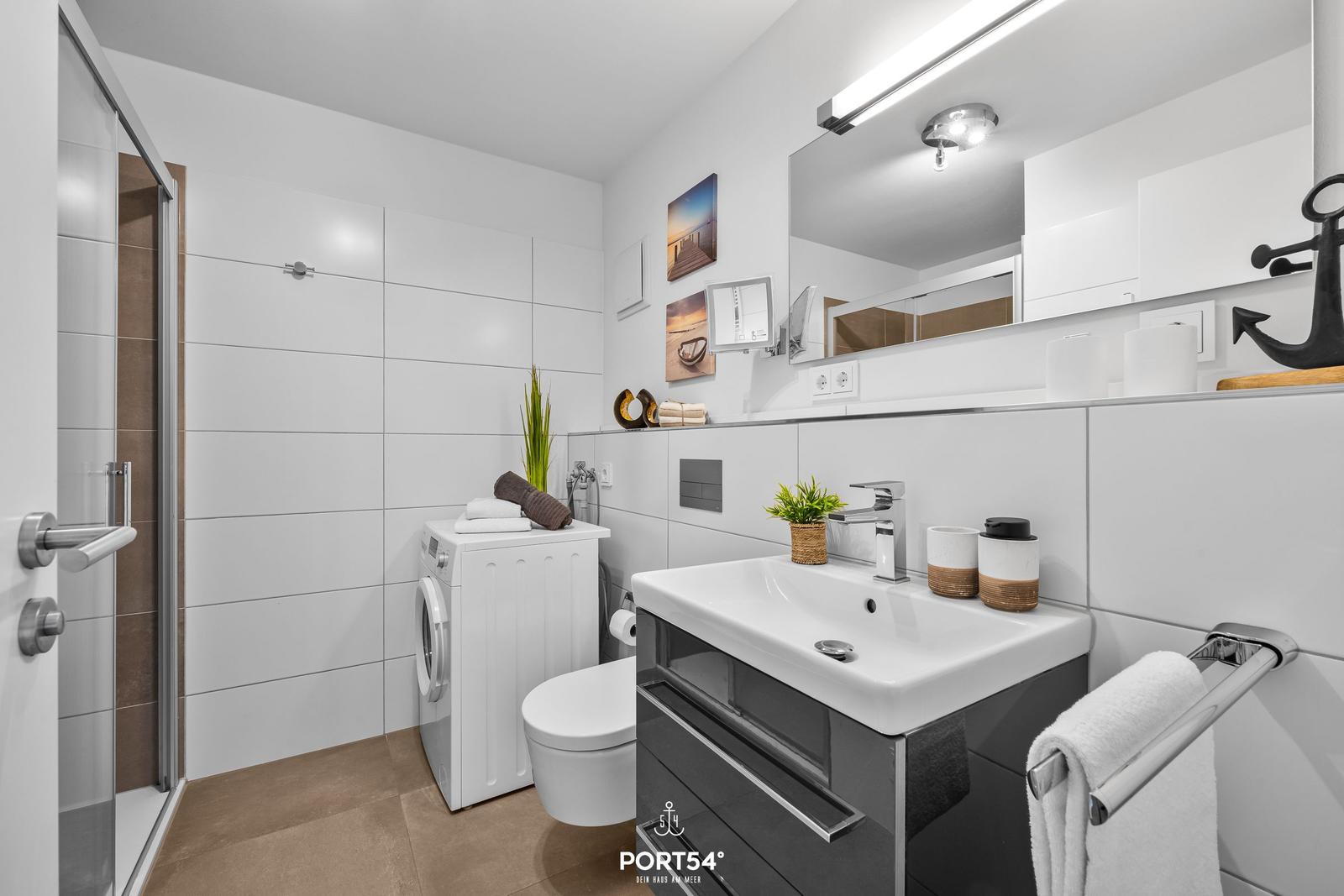 Badezimmer mit Dusche, Waschmaschine und Waschtisch