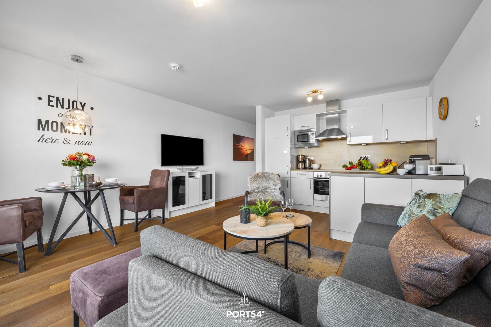 Wohnbereich mit Küche, Sofa, Esstisch und Fernseher.