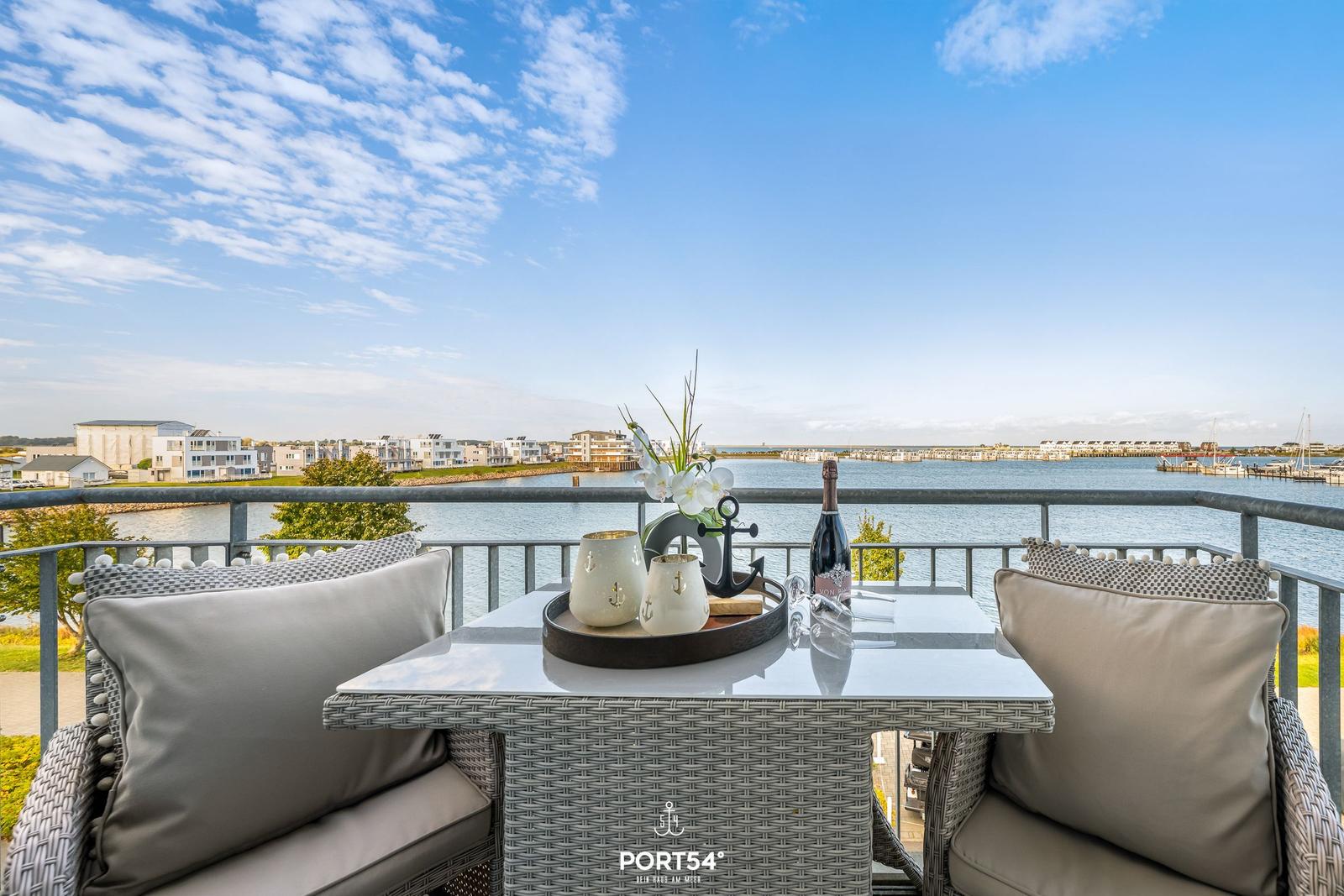 Terrasse mit Tisch und Stühlen, Blick auf Wasser und Häuser
