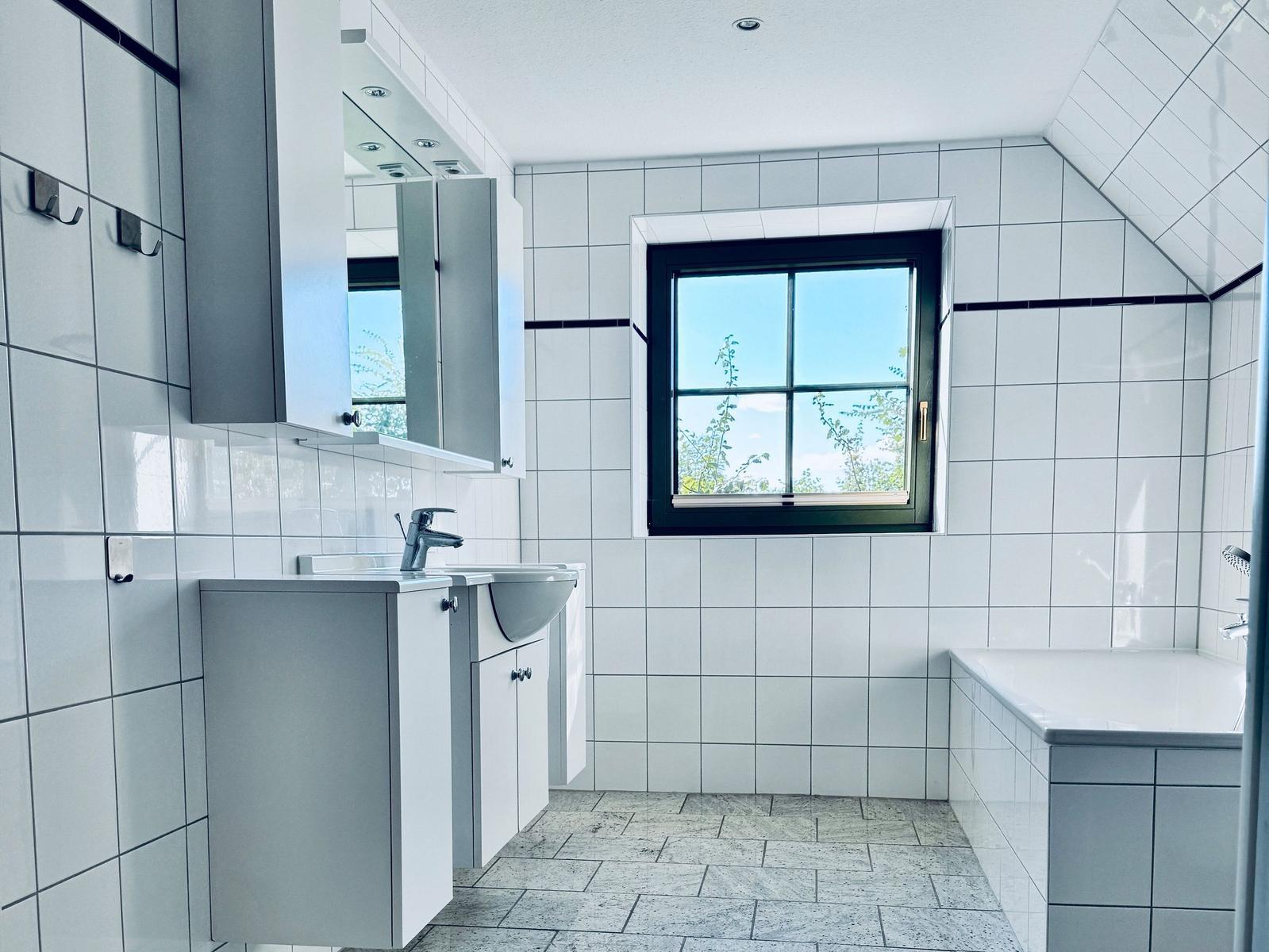 Badezimmer mit Waschbecken, Badewanne und Fenster