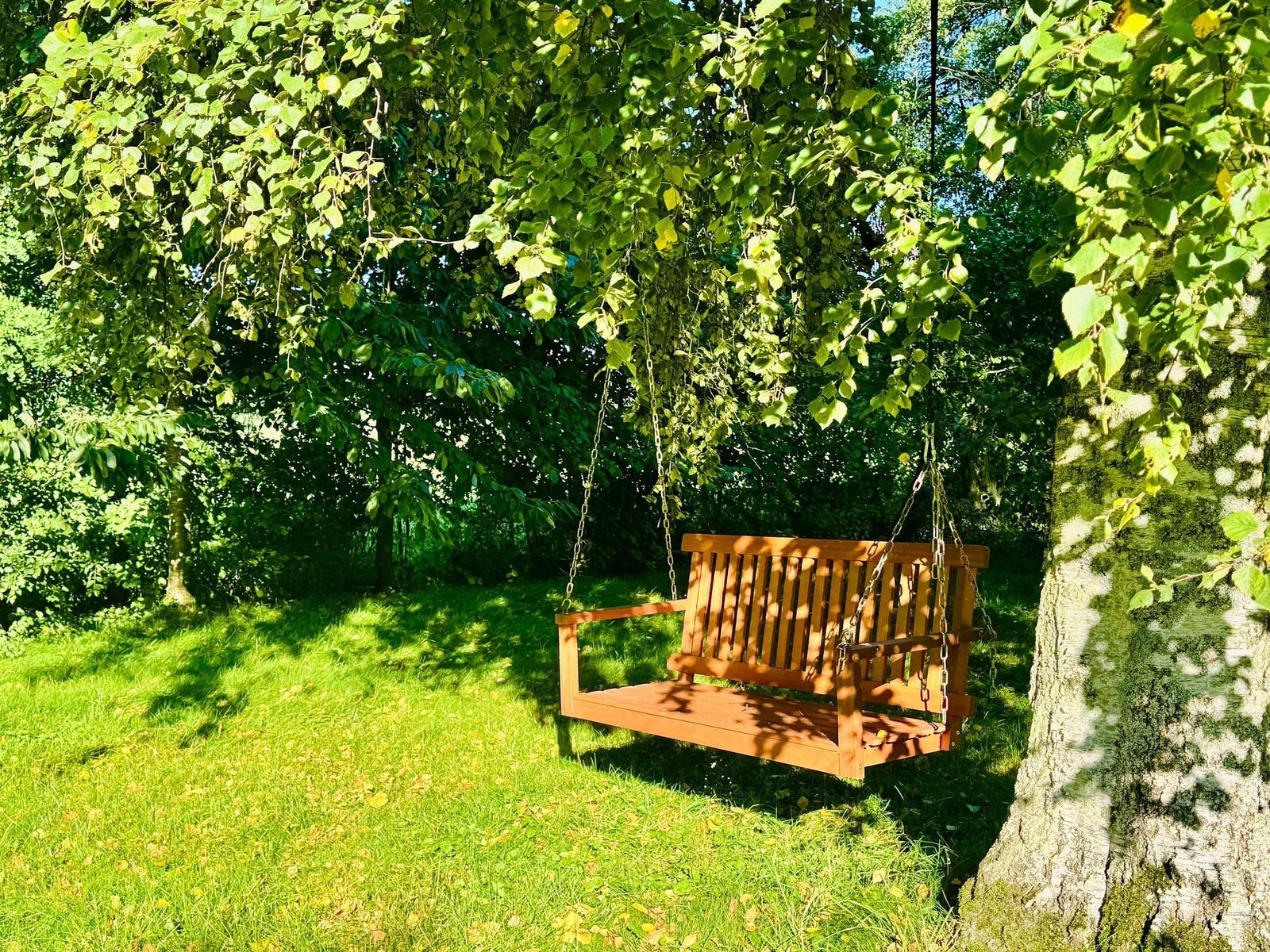 Holzschaukel unter Bäumen im Garten