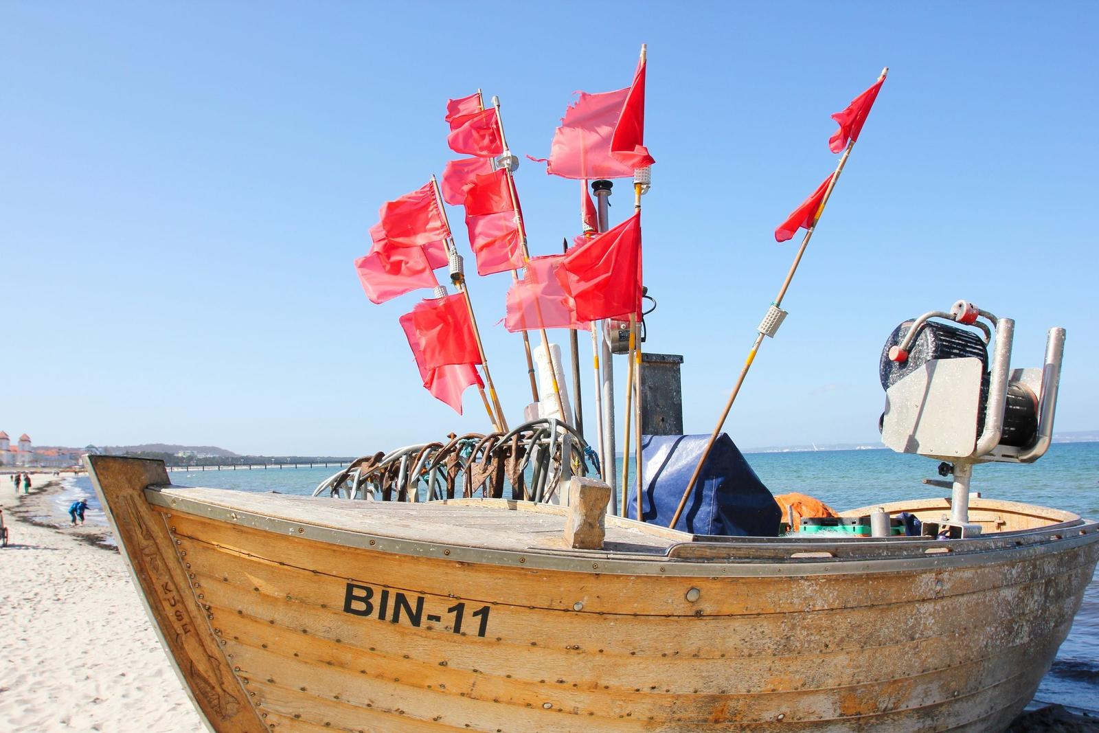 Holzboot mit roten Flaggen am Strand