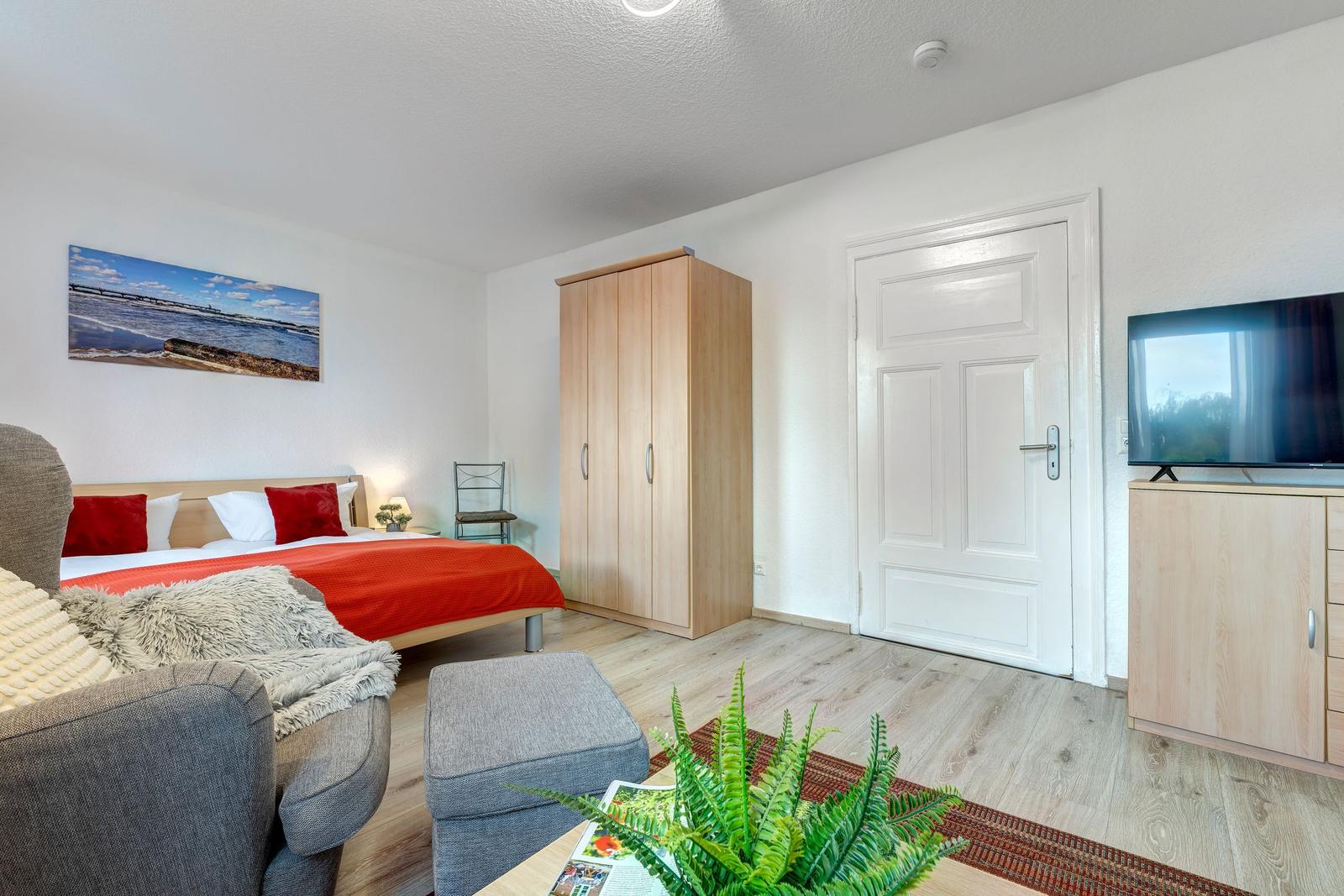 Schlafzimmer mit Bett, Kleiderschrank und Fernseher.