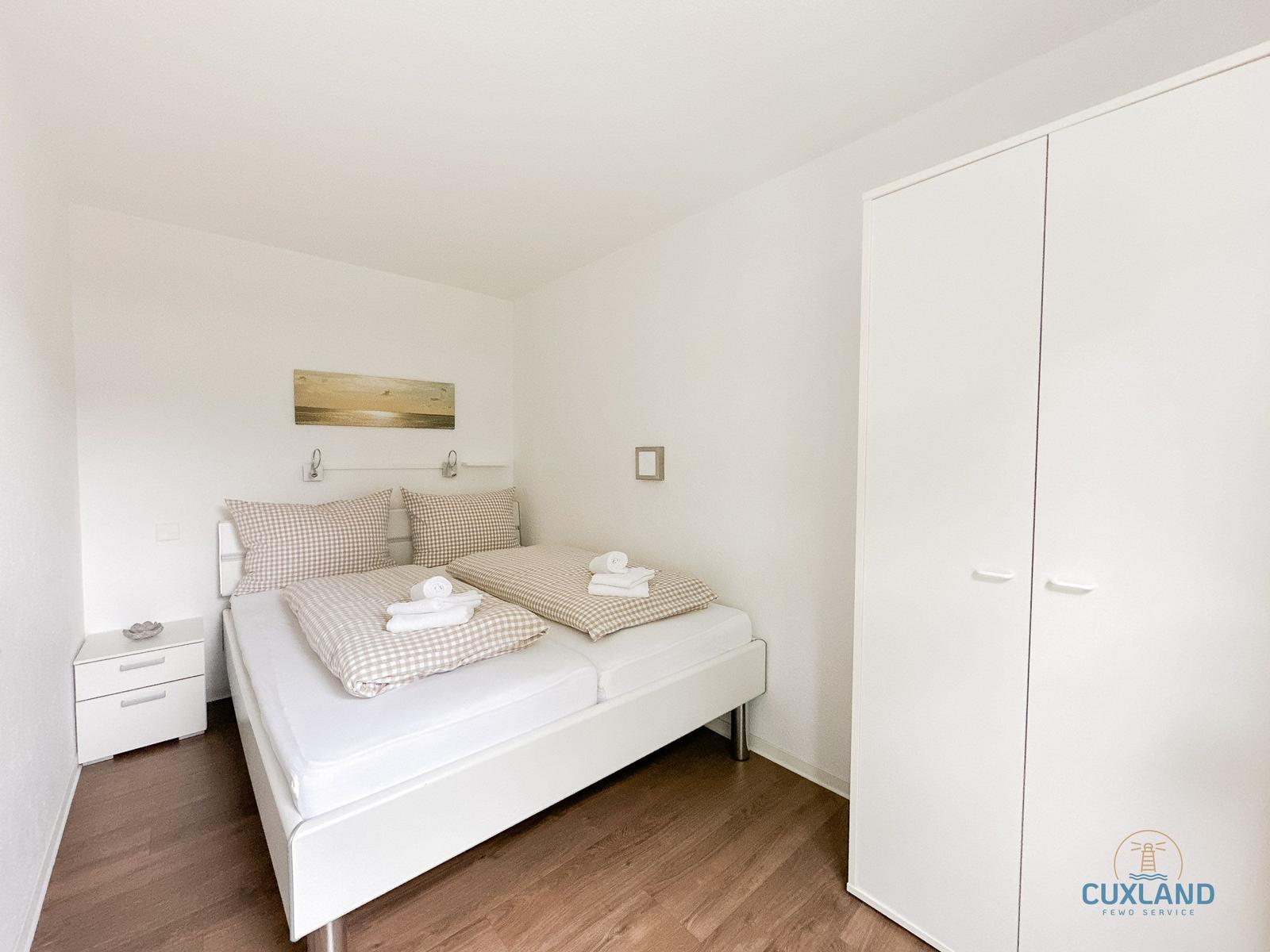 Schlafzimmer mit Doppelbett, Kleiderschrank und Nachttisch.