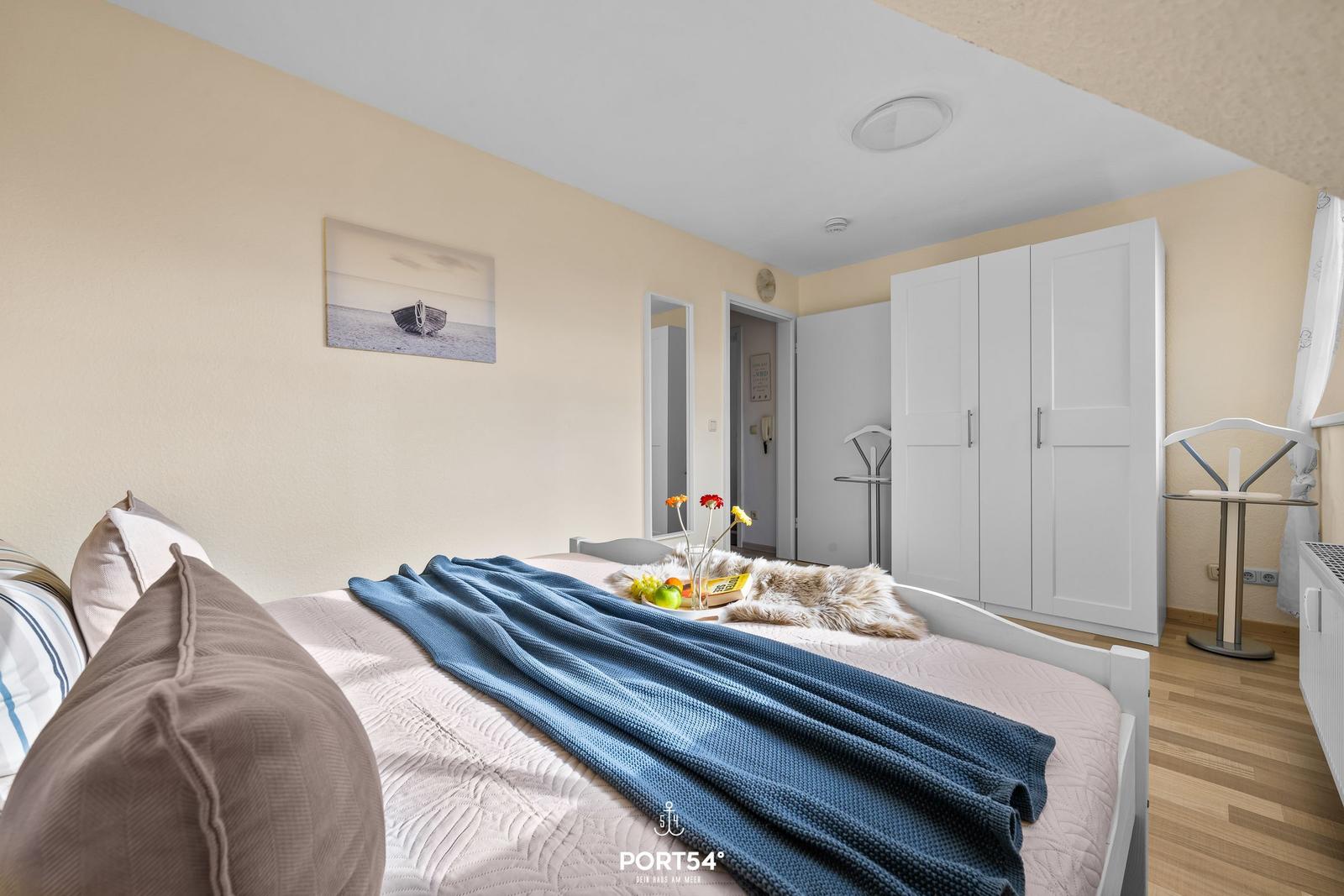 Schlafzimmer mit Bett, Kleiderschrank und Wandbild