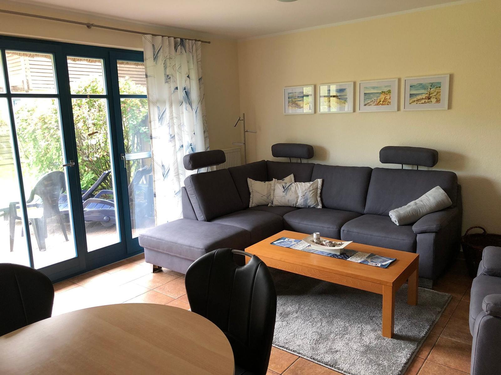 Wohnzimmer mit Sofa, Couchtisch und Glastür zur Terrasse.