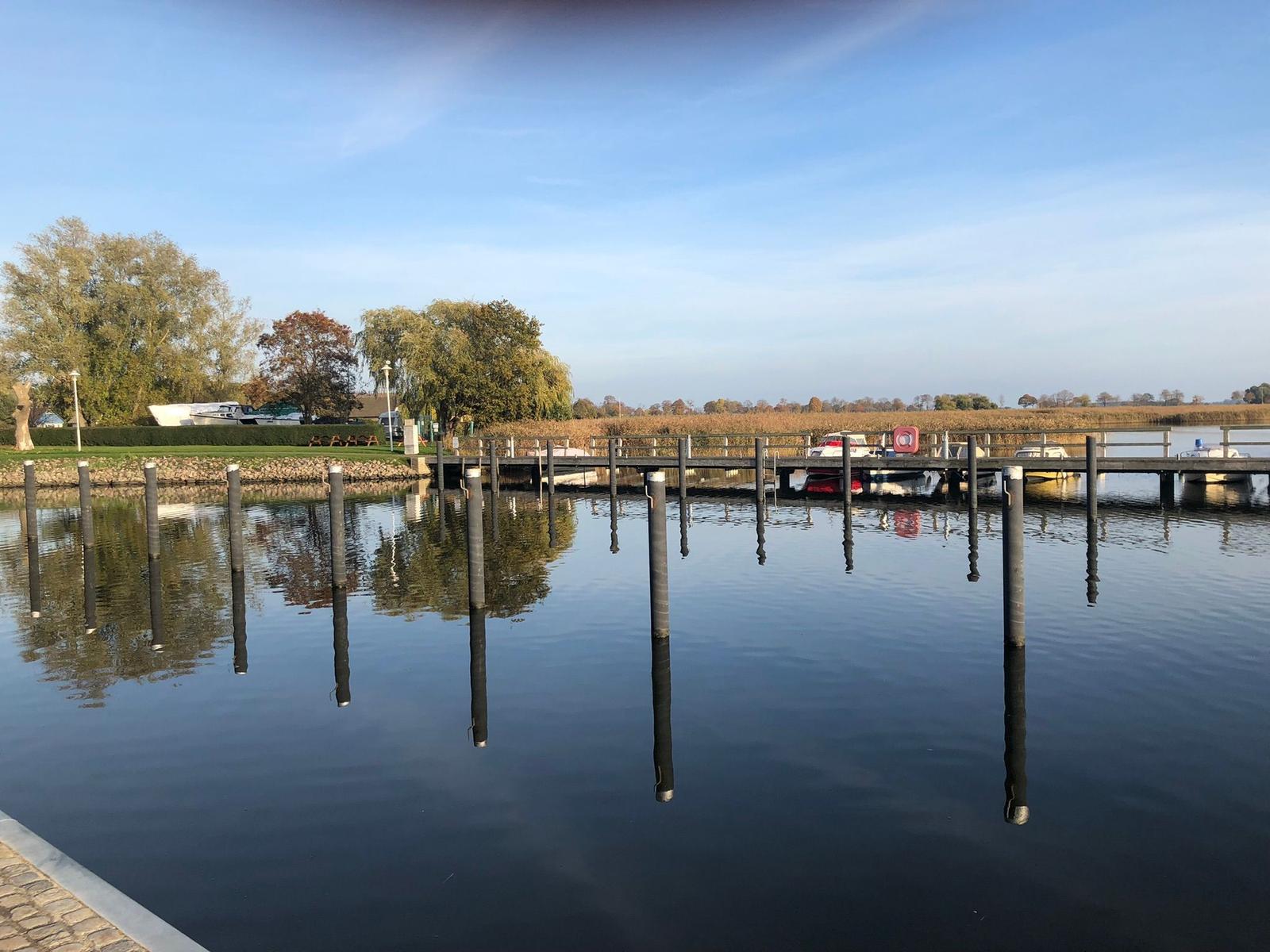 Hafen mit Stegen und Booten an ruhigem Wasser unter blauem Himmel.