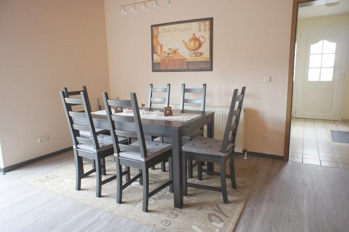 Esszimmer mit Tisch, sechs Stühlen und Wandbild.