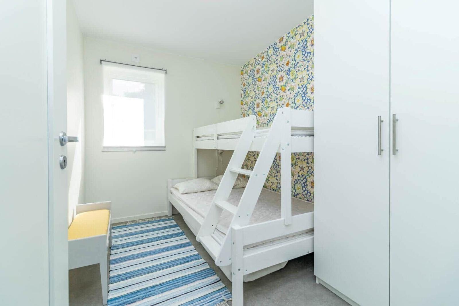 Zimmer mit Doppelstockbett, Fenster und Kleiderschrank.