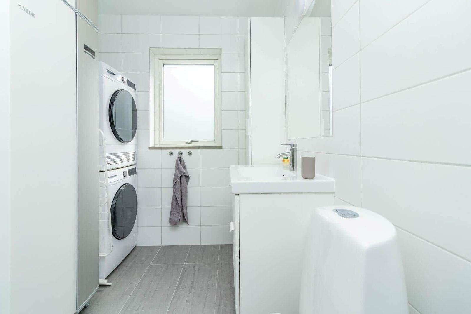 Badezimmer mit Waschmaschine, Spülmaschine und Toilette.