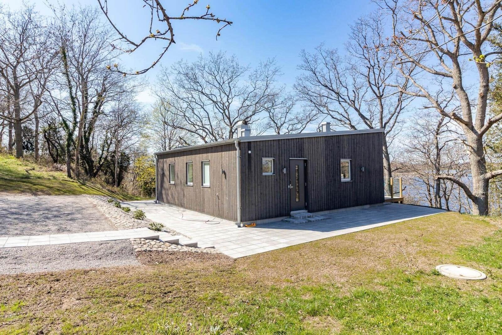 Moderne Holzhütte mit Terrasse und Blick auf Wasser.