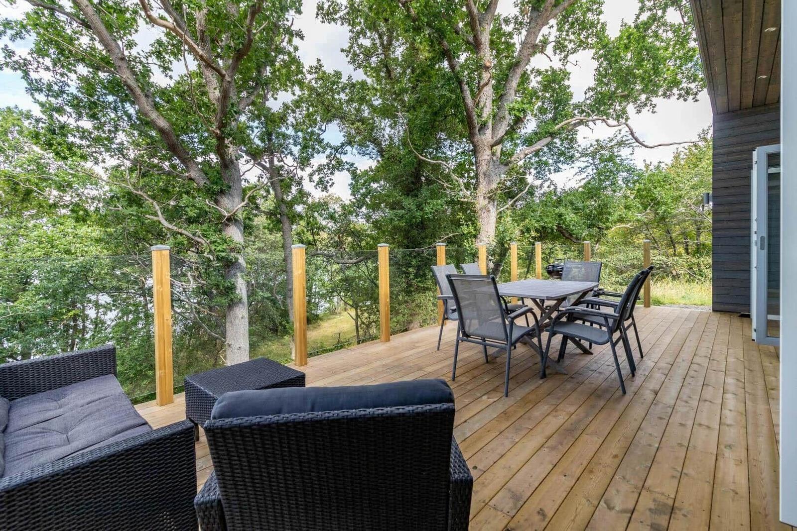 Terrasse mit Sitzgruppe und Esstisch unter Bäumen.