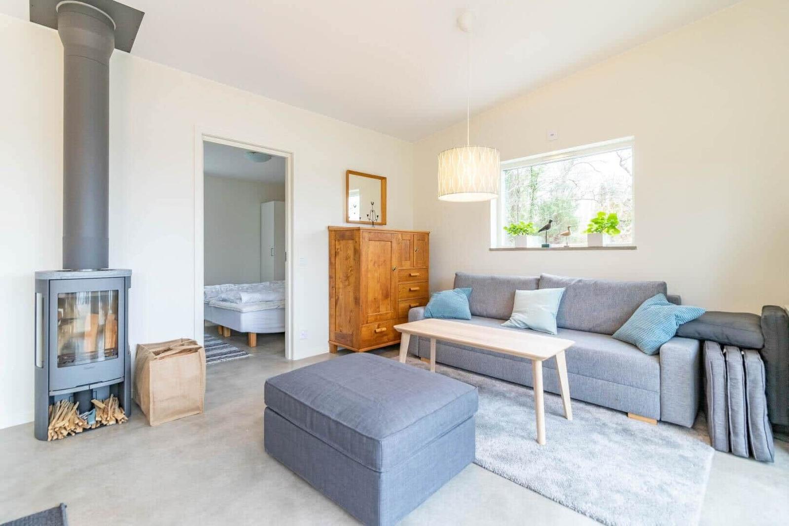 Wohnzimmer mit Sofa, Couchtisch und Kaminofen. Durchgang zur Schlafzimmer.