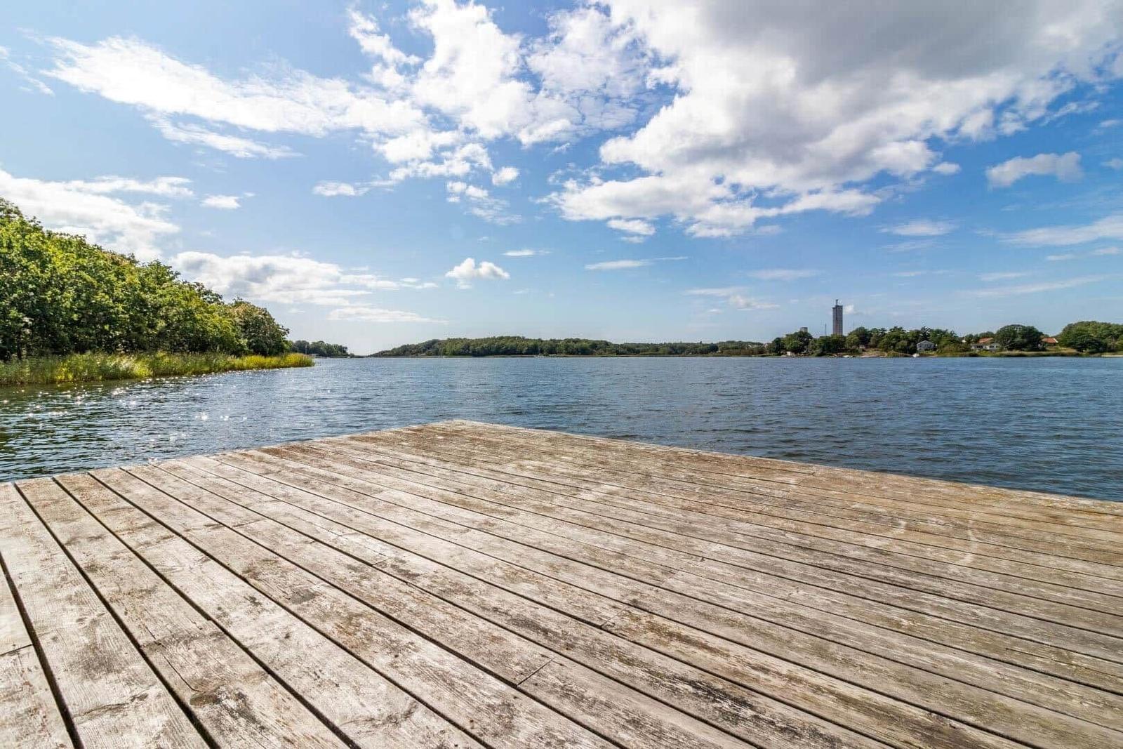 Holzterrasse am See mit Blick auf bewaldeten Ufer und Turm.