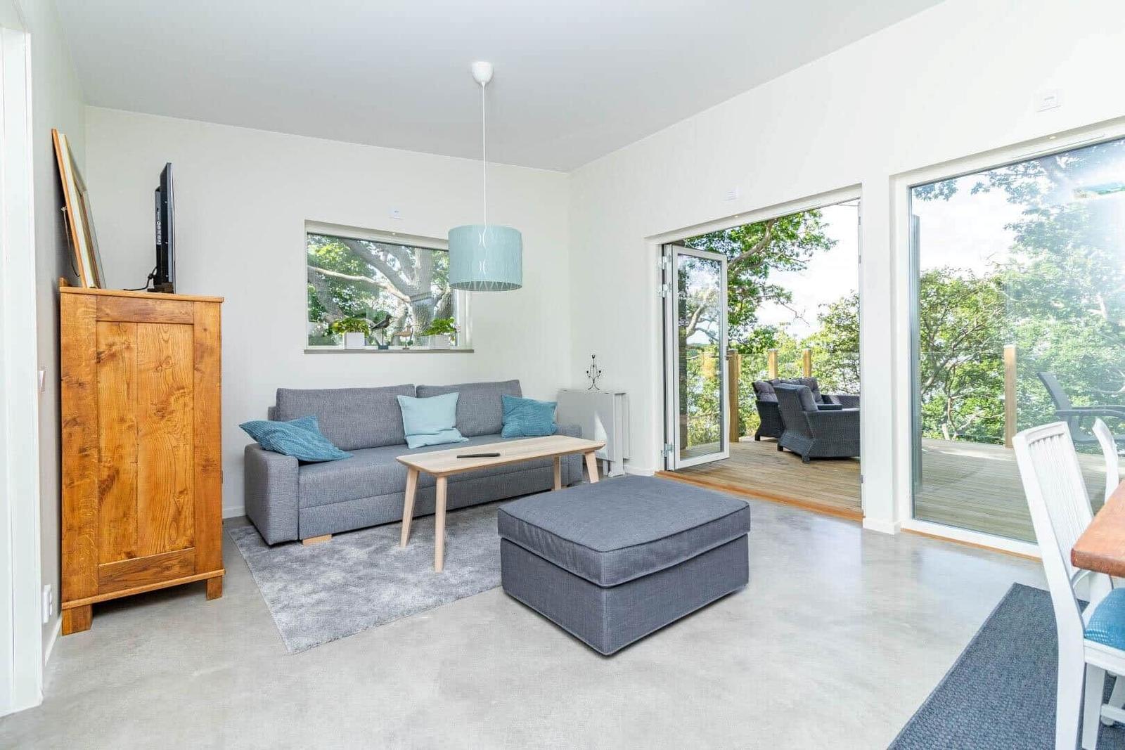 Wohnbereich mit Sofa, Couchtisch und Terrasse mit Blick auf Grünflächen.