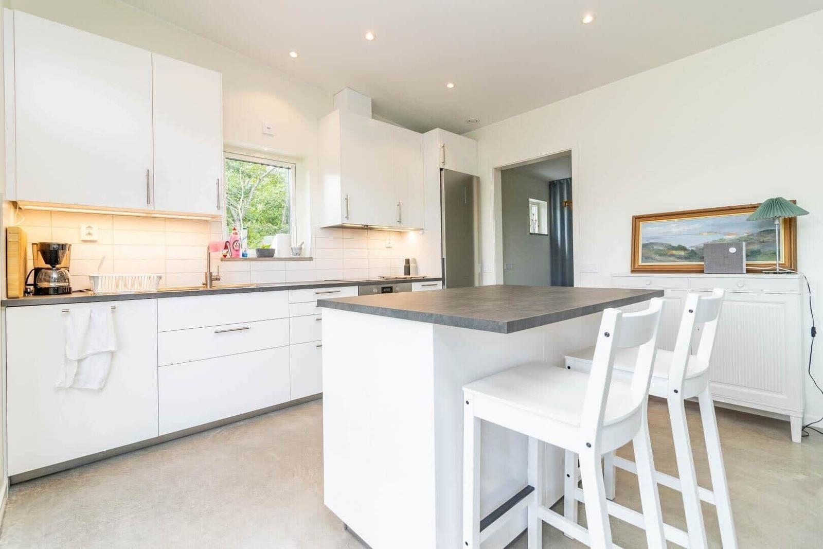 Moderne Küche mit weißen Schränken und Kücheninsel mit Sitzhöhe.