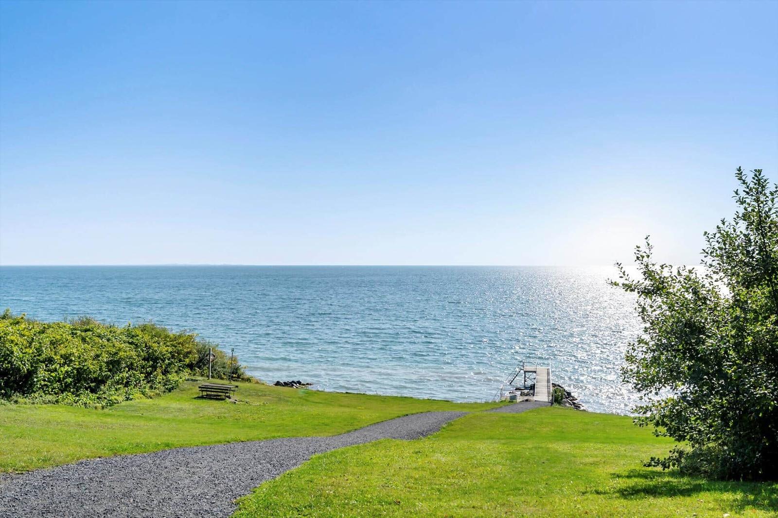 Grüner Hang mit Blick auf das Meer und einem Steg.