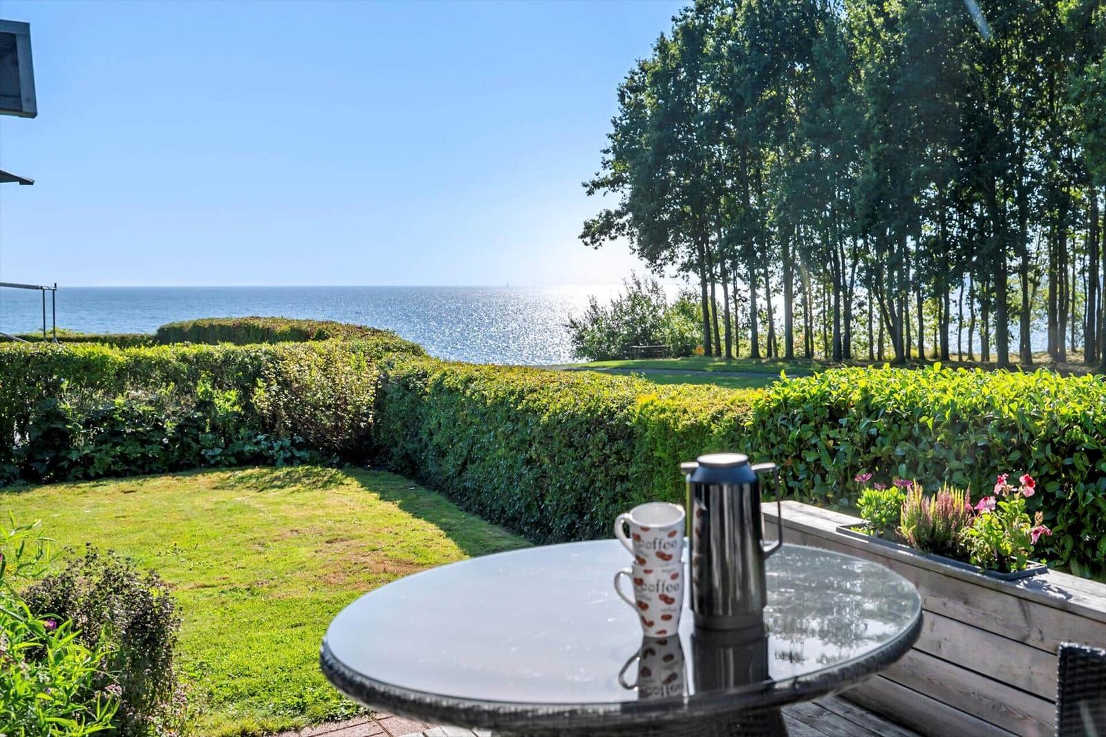 Garten mit Tisch, Blick auf Meer und Bäume.