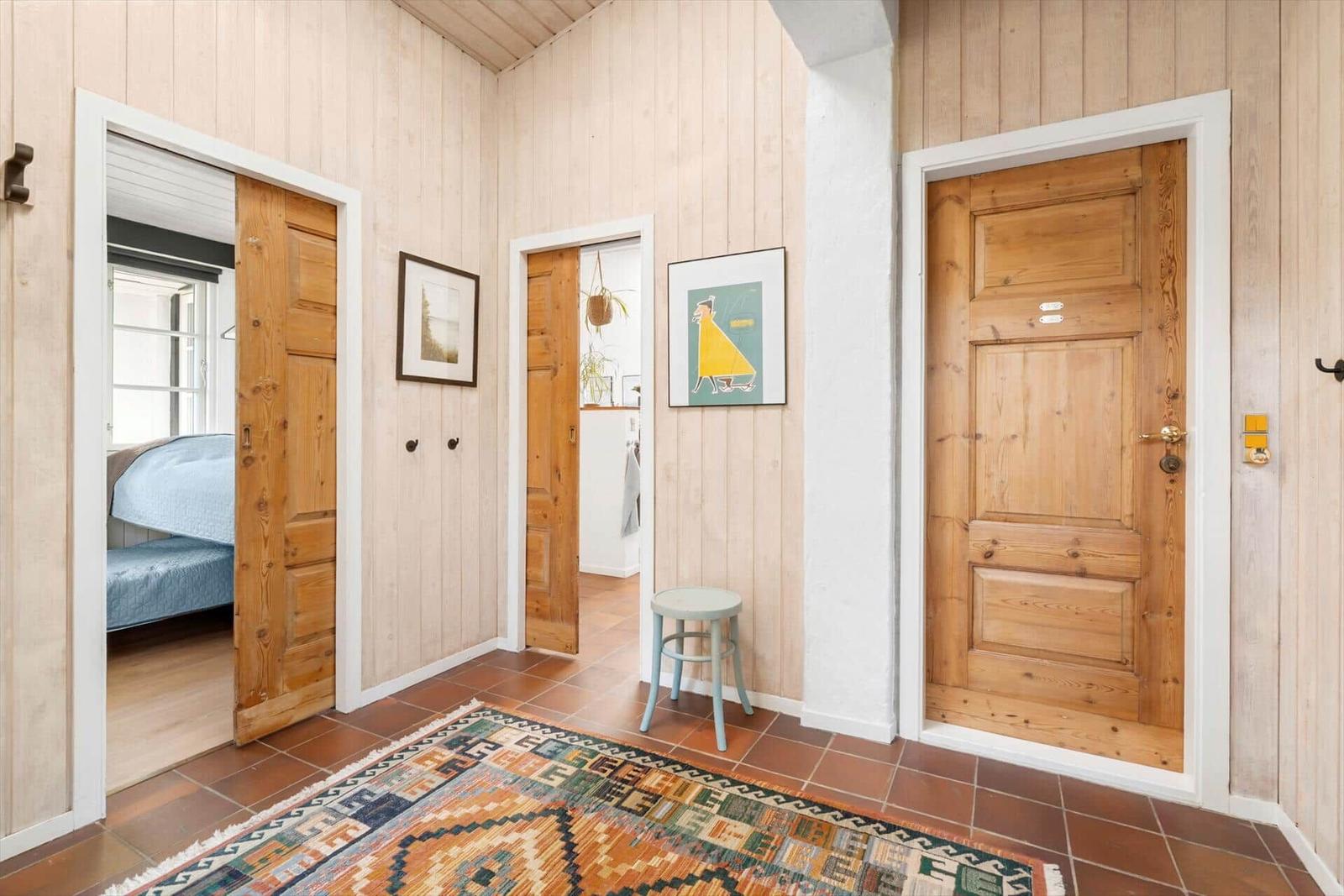 Hausflur mit Holztüren, Teppich und Wandbildern