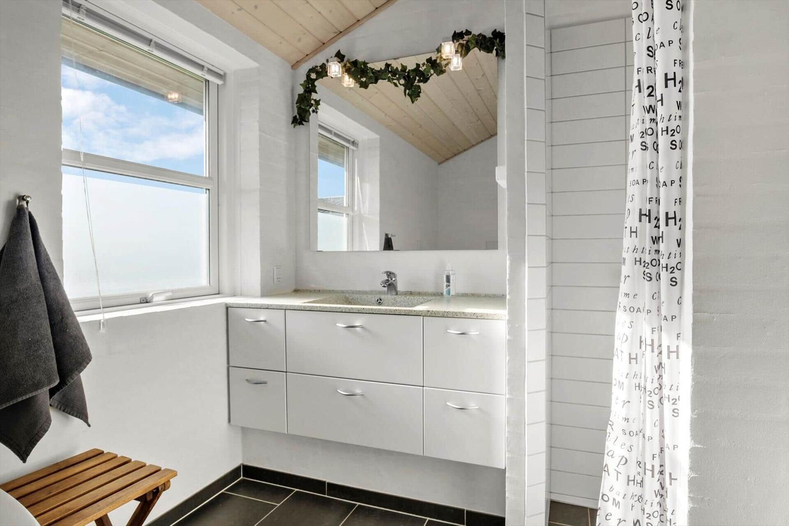 Badezimmer mit Waschbecken, Spiegel, Dusche und Fenster mit Blick.