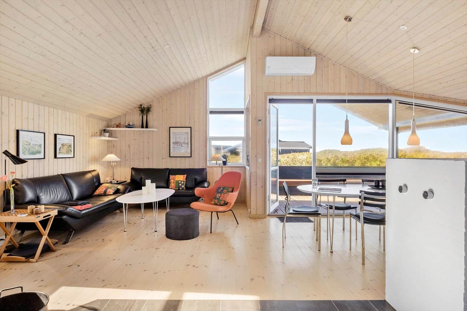 Wohn- und Essbereich mit Holzwand und großem Fenster. Möbel und Einrichtung sind modern.