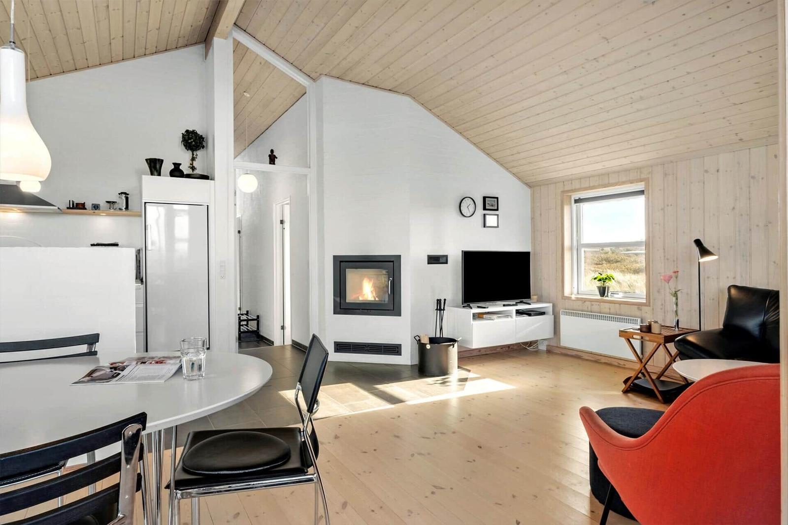Wohnbereich mit Esstisch, Kamin und TV. Holzdecke und -boden.