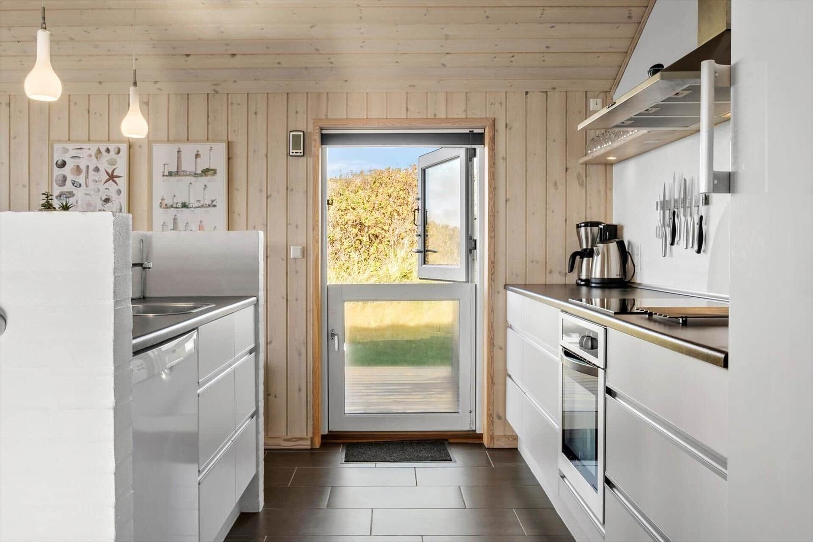 Küche mit Holzwand, Glas-Tür und weißen Schränken.