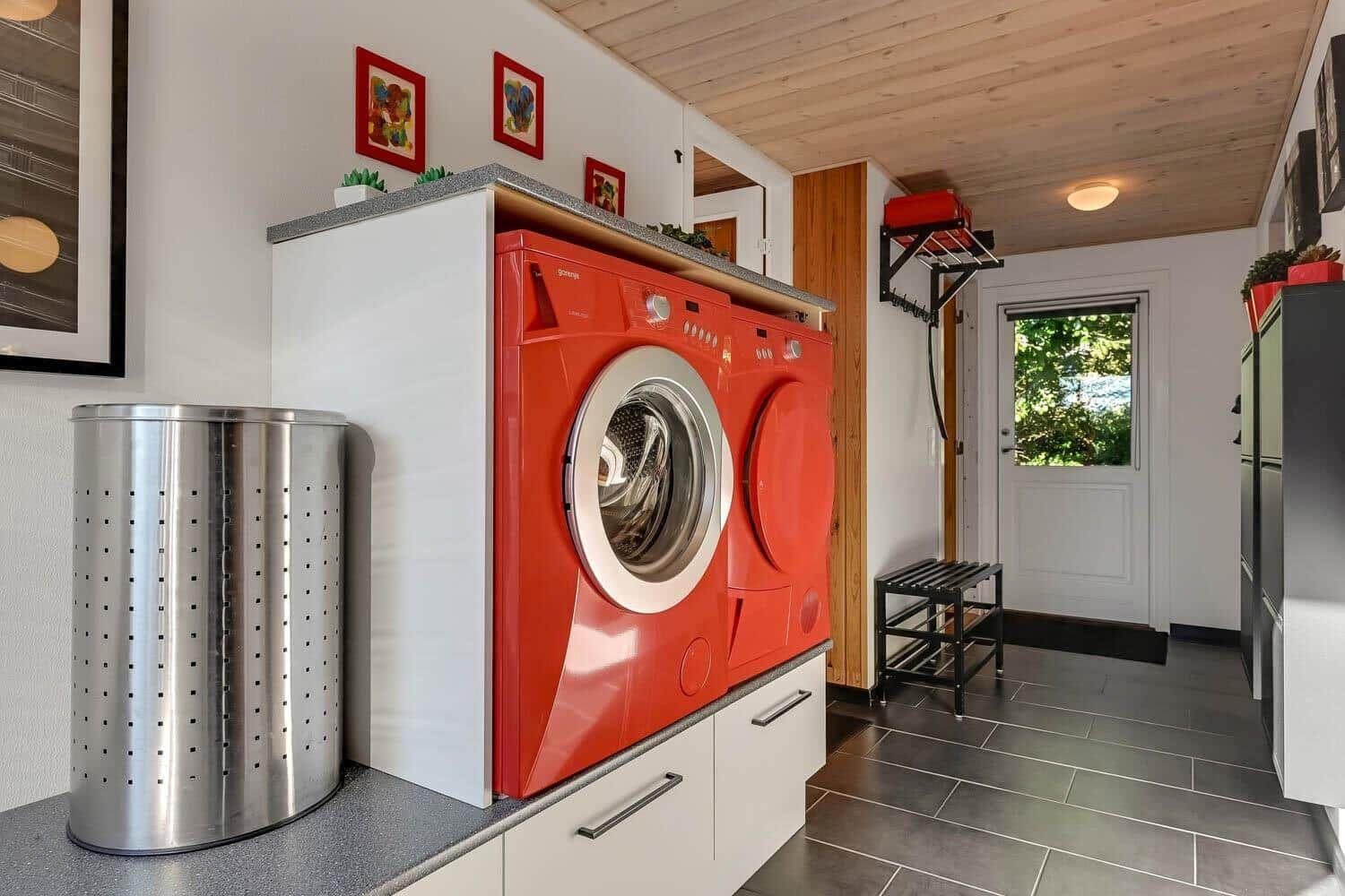 Laundry room with red washing machine and dryer, gray floor, and wooden ceiling.