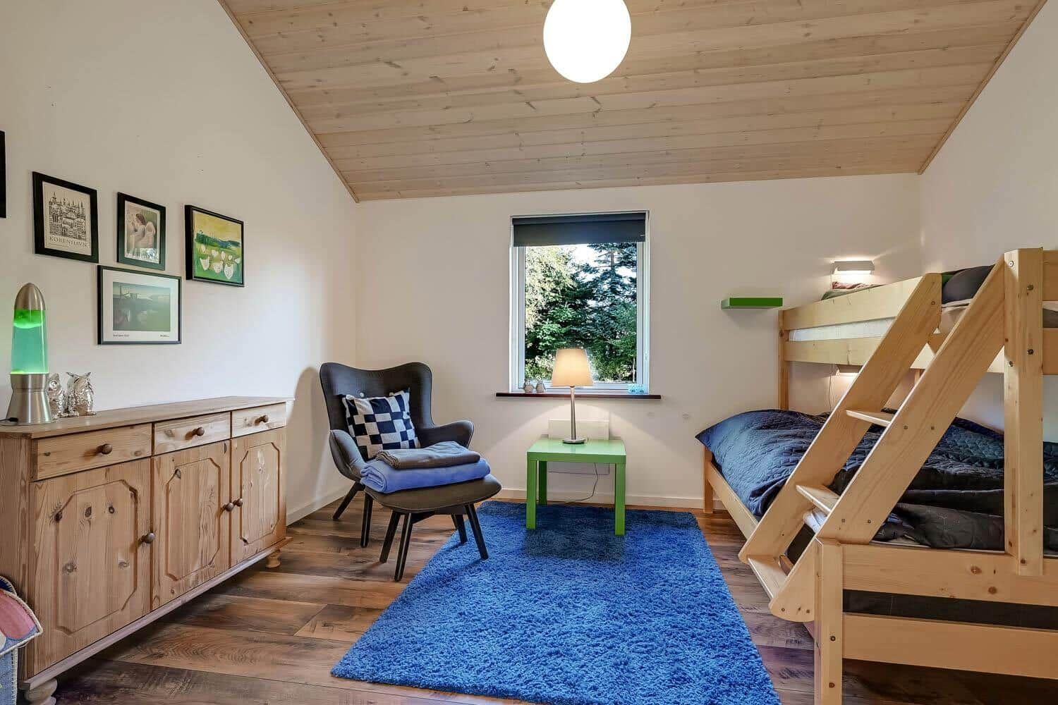 Bedroom with wooden floor, bunk bed, and blue rug.