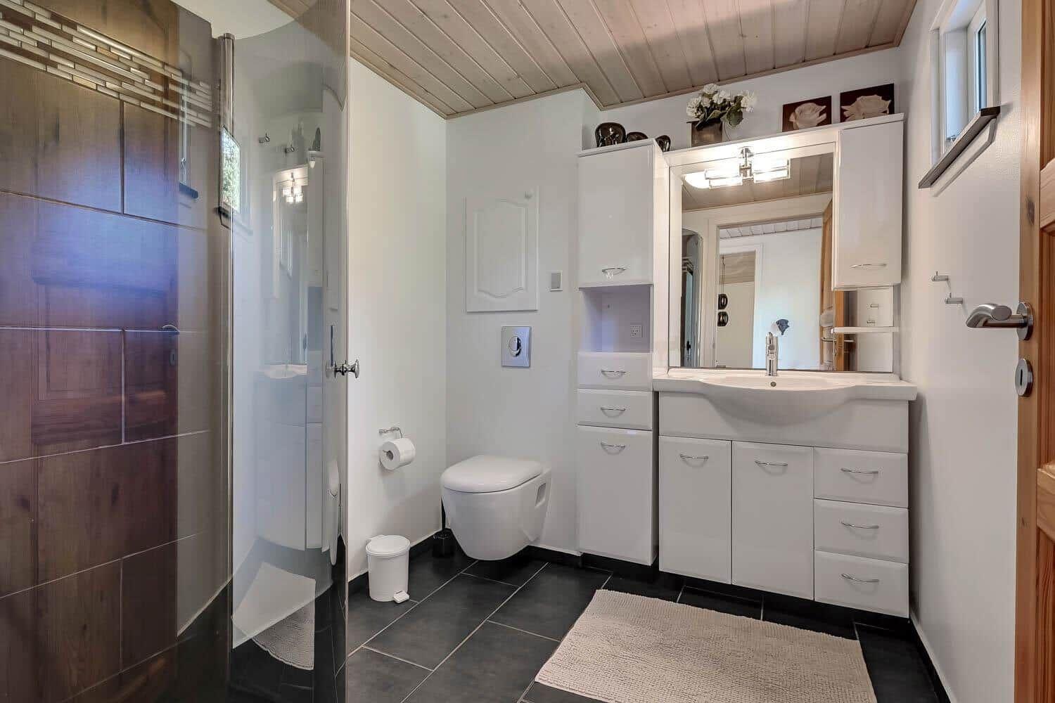 Bathroom with shower, toilet, and sink with mirror.