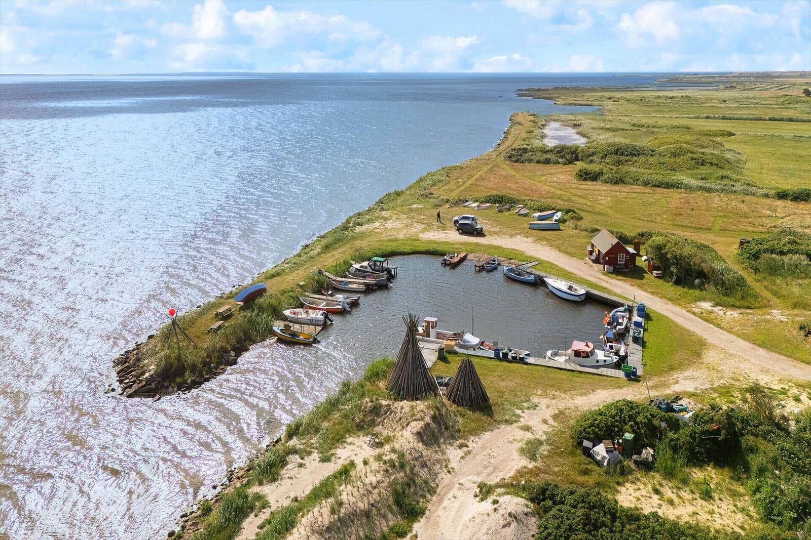 Hafen mit Booten an Küste, grüne Landschaft und rotes Haus